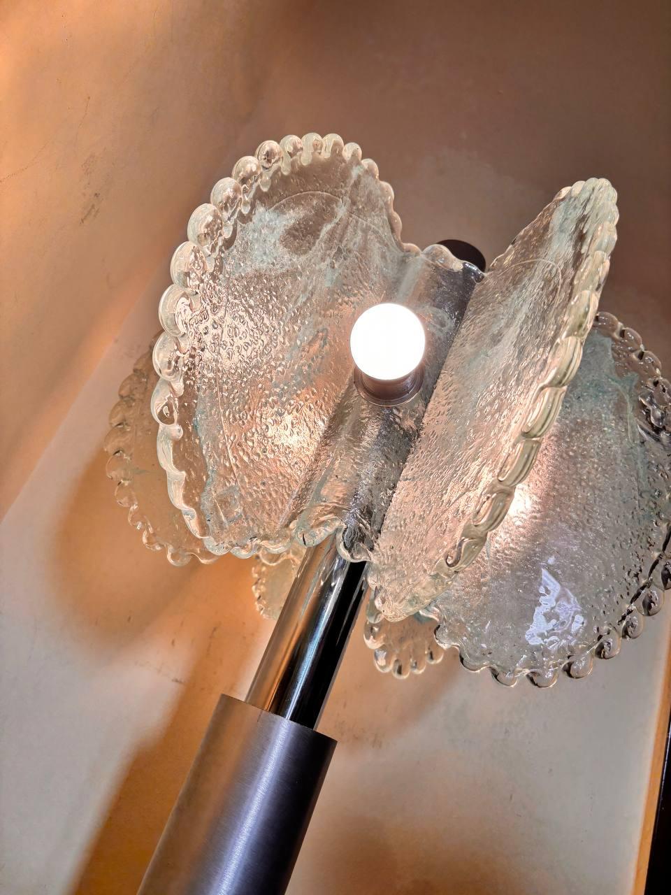 Cette lampe de table est une création artistique du maître Mazzega de Murano, célèbre pour son habileté à travailler le verre vénitien. Elle se distingue par un design raffiné qui allie modernité et tradition, avec trois lampes qui éclairent la
