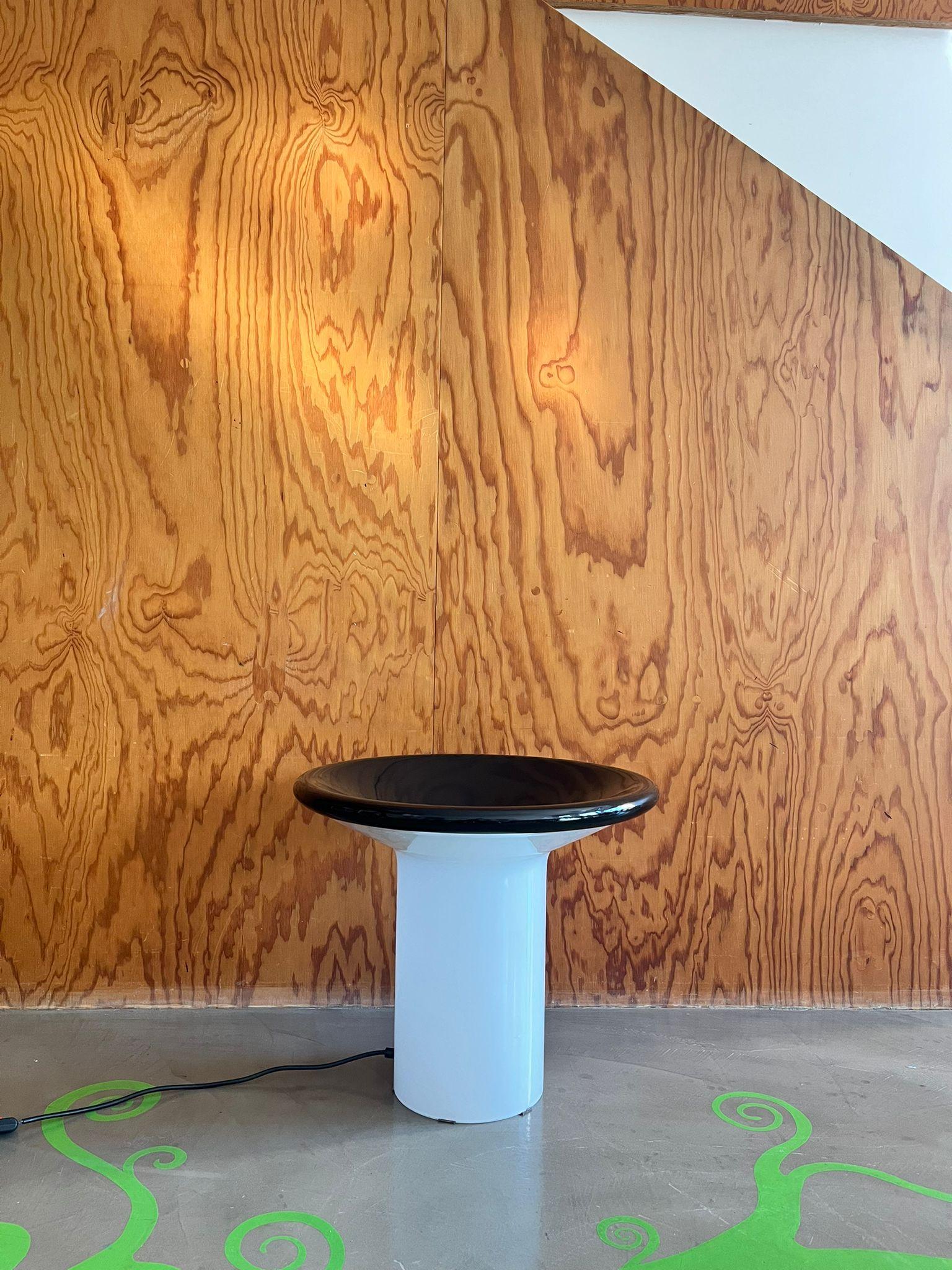 Lampada da tavolo in vetro lattiginoso e metallo nero, 1970 circa.

Lámpara de mesa caracterizada por una base de metal lattiginoso que confiere a la estructura un aspecto refinado. La parte superior, realizada en metal barnizado negro opaco, crea