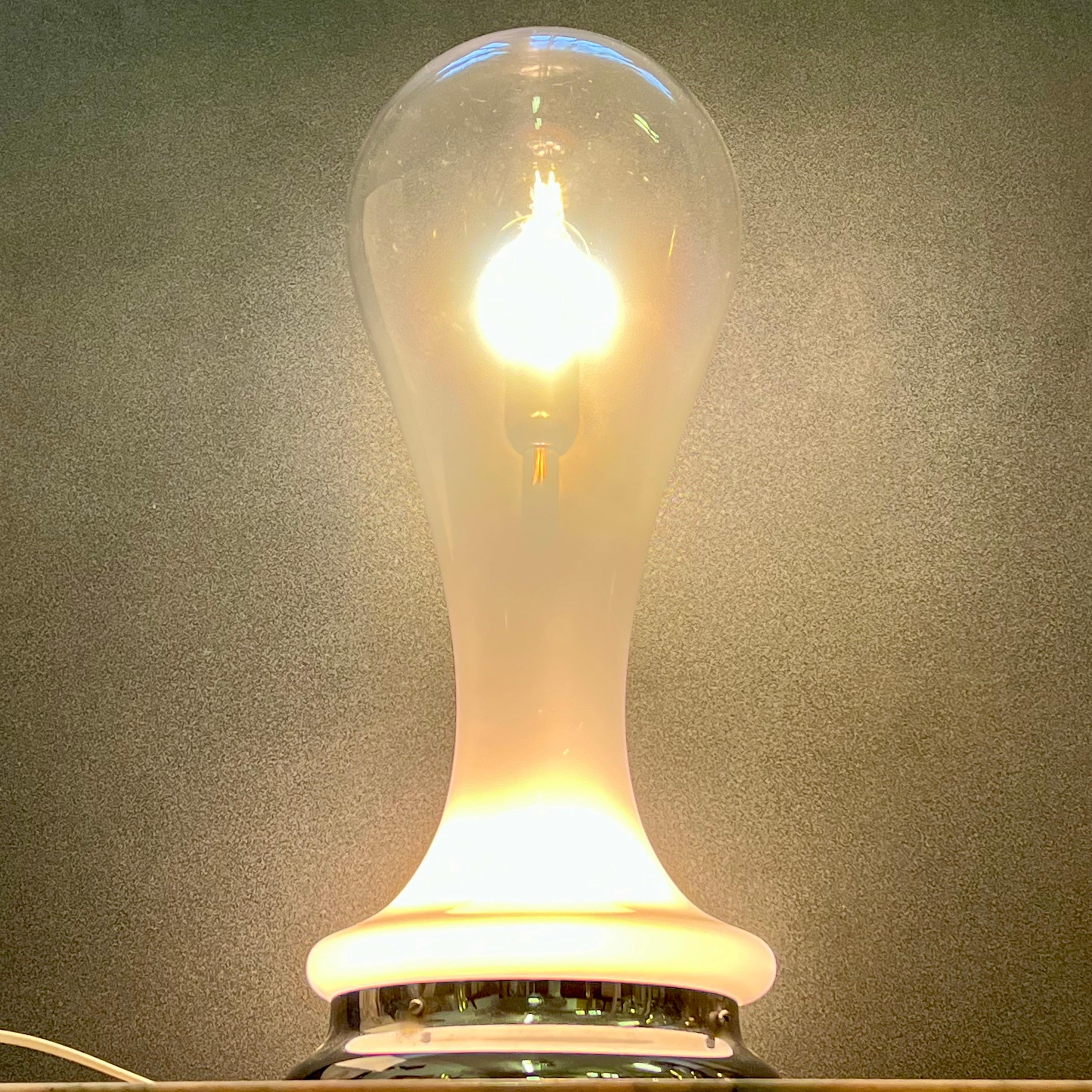 Splendida lampada da tavolo in vetro lattimo soffiato, attribuita a Carlo Nason, per la storica vetreria A.V. Mazzega, realizzata negli anni ’70. 
Questa affascinante creazione si distingue per la sua forma scultorea fluida e sinuosa, che richiama