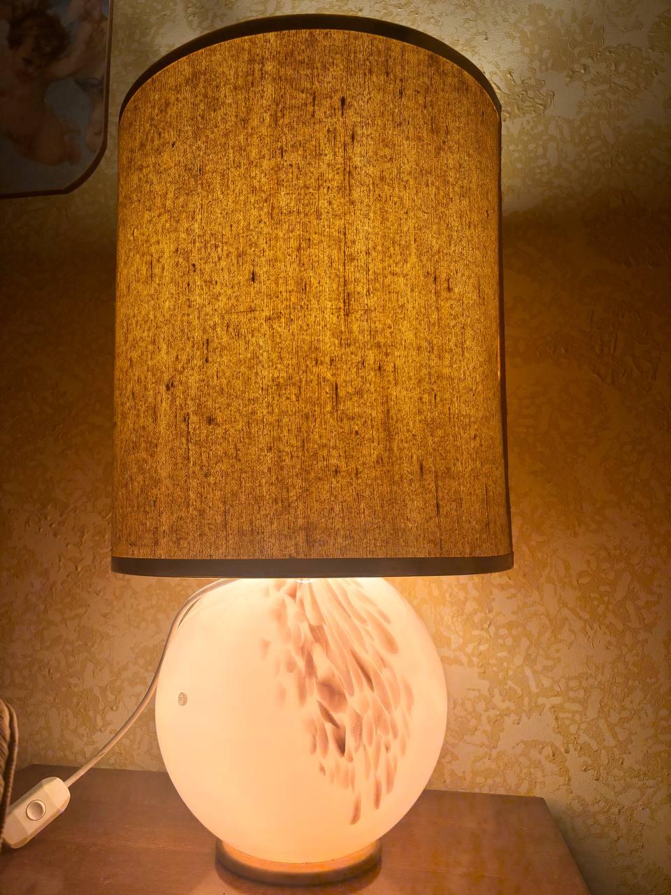 Sumérjase en la sofisticada belleza de la artesanía veneciana con esta hermosa lámpara de mesa de La Murrina. Con un diseño icónico, la base de cristal soplado opalescente llama la atención por sus delicados matices y sus inserciones de cristal de