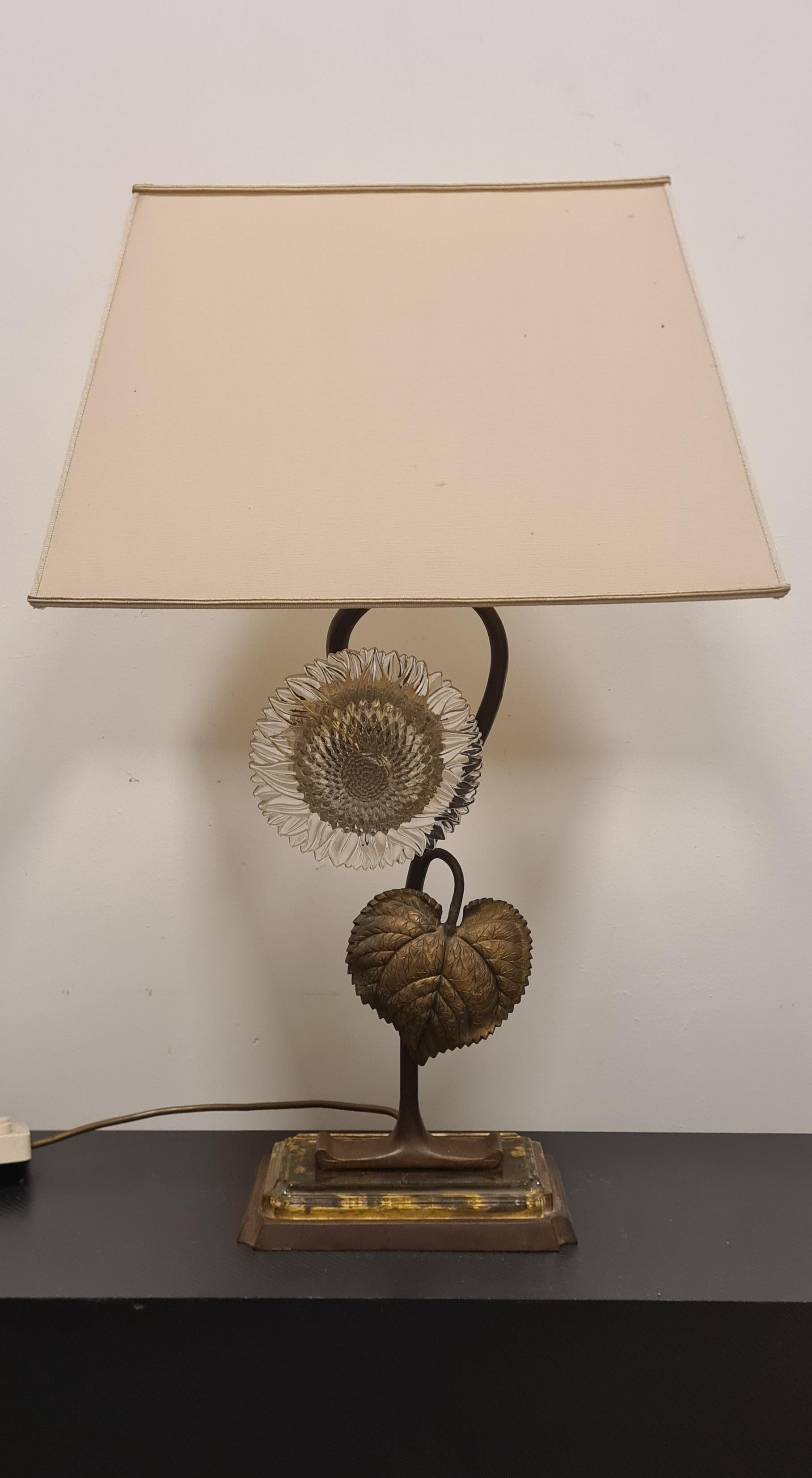 Refined bronze and glass sunflower table lamp.

This elegant lamp features a bronze and glass base from which a bronze sunflower stem grows.

The corolla of the sunflower is given by a worked glass disc.

The lamp has several lighting modes, either