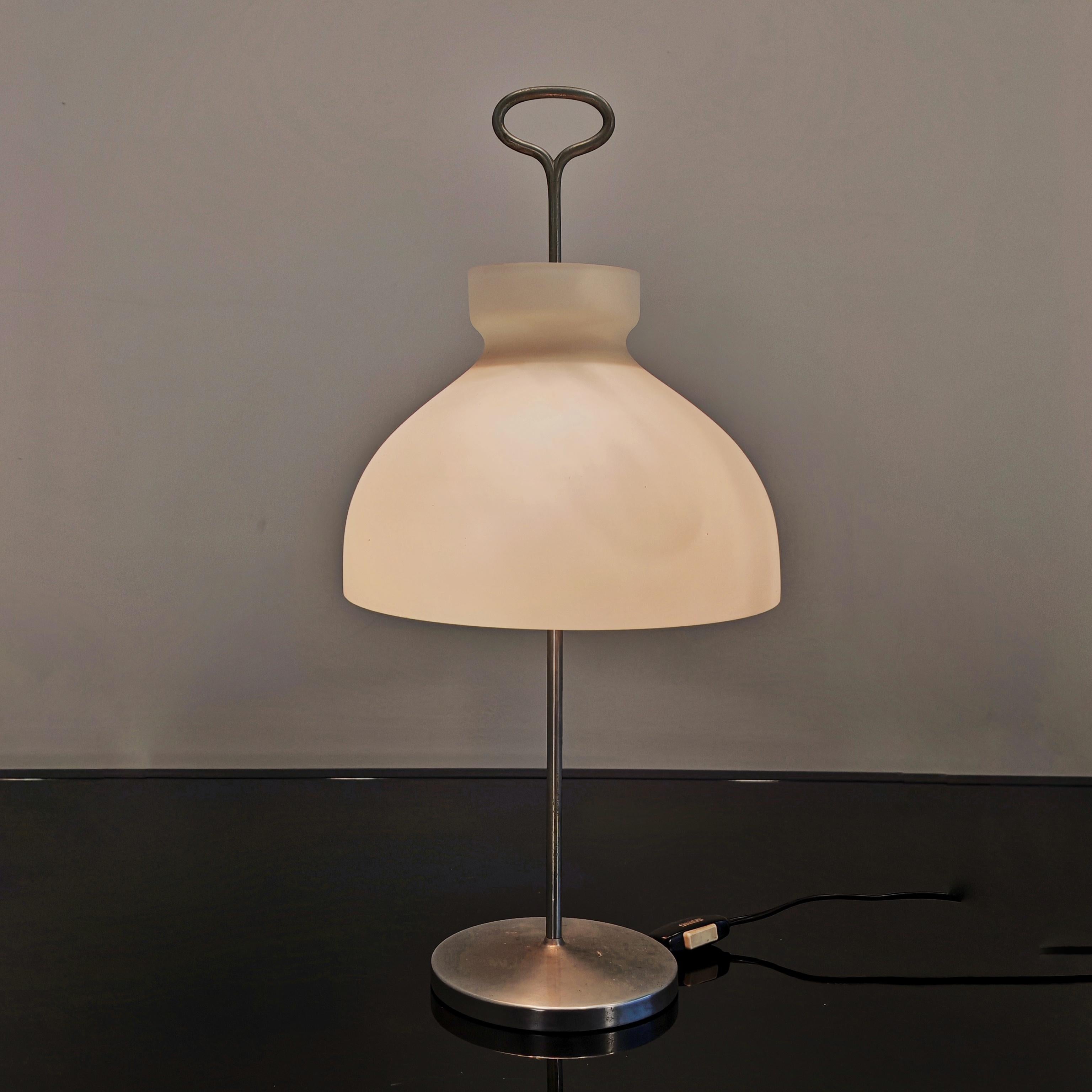 La lampada Arenzano disegnata da Ignazio Gardella nel 1956 per Azucena è una raffinata rivisitazione raffinata della classica abat-jour. La struttura è in ottone nichelato, mentre il diffusore è una campana in vetro opalino soffiato di diametro cm