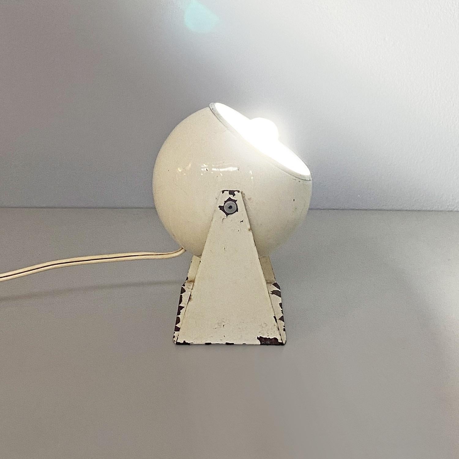 Wall or table lamp with white painted metal frame, with a central spherical-shaped spotlight, which can be directed by the rotation mechanism present on the two supporting side fins. Diffuser provided on the inside with an aluminum cover, with a