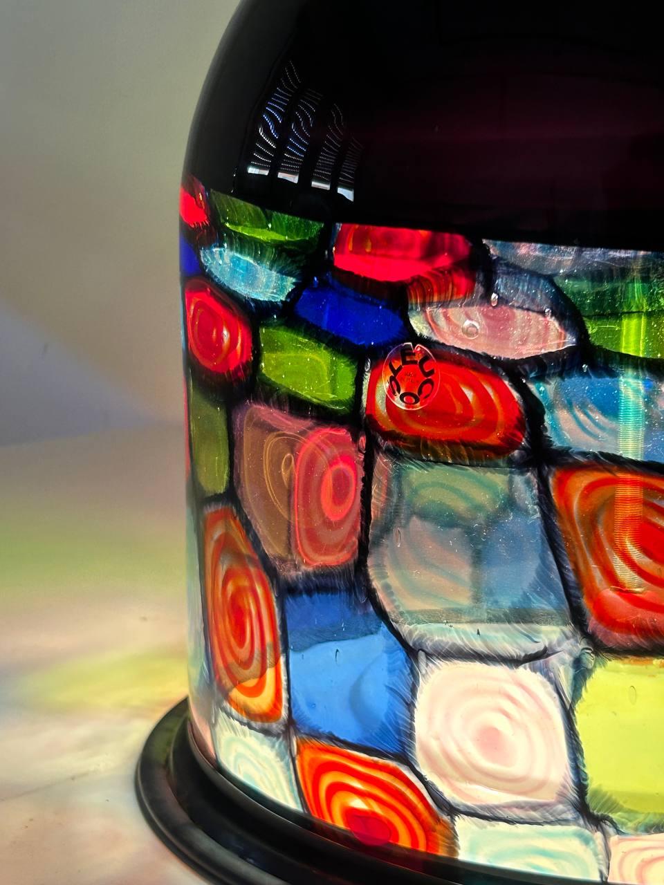 Rara versione lampada da tavolo prodotta da Leucos, bollino originale presente, e disegnata da Renato Toso.  

Il vetro decorato e fatto artiginalmente a murano proietta sul piano un suggestivo gioco di luci.

condizioni coeve con l'età, non