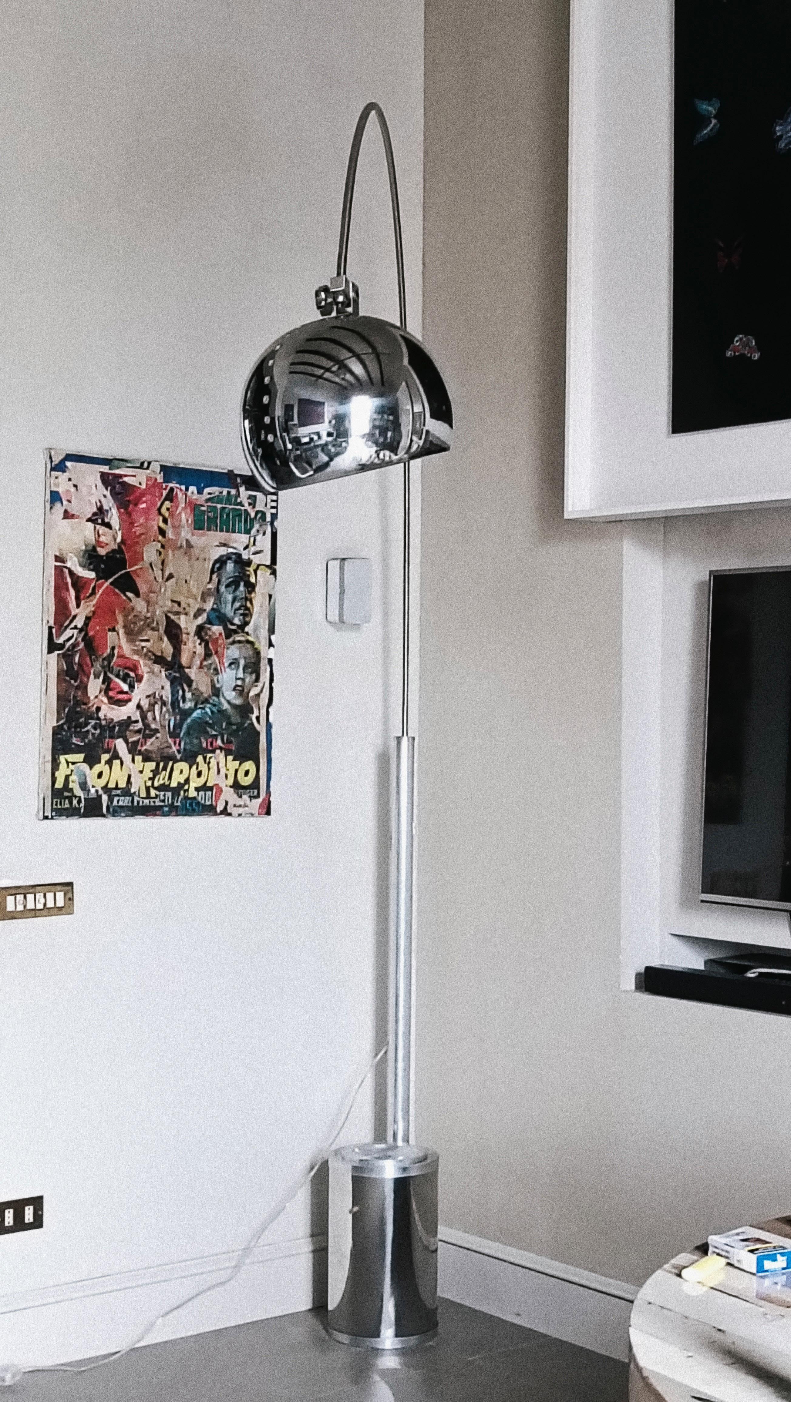 Lampada da terra ad arco Space Age in metallo cromato, anni '70. Realizzata con un arco  sostenuto da una base molto ampia, costituita da un cilindro ricoperto da una piastra in acciaio cromato su cui è inserito un posacenere. L'inclinazione è