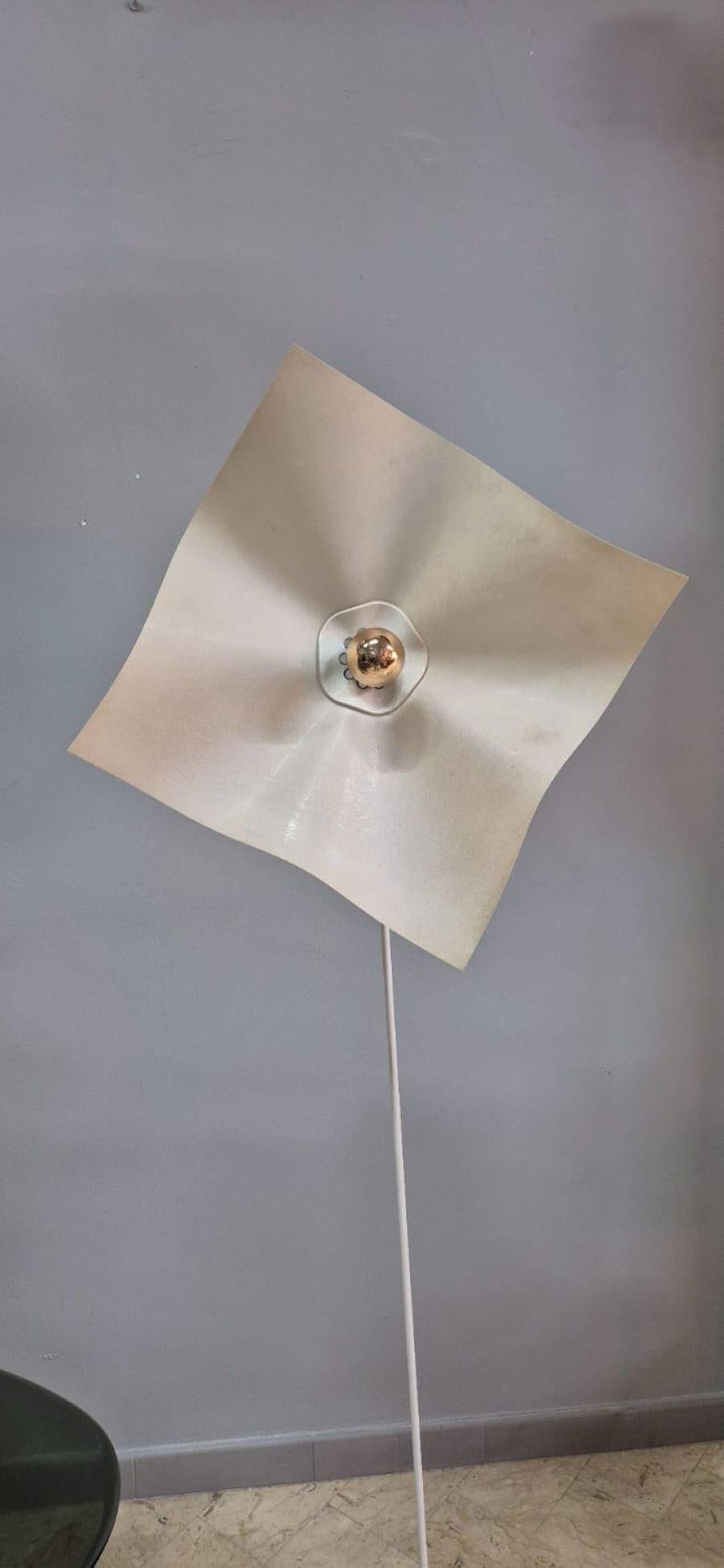 Stehleuchte bestehend aus einem grau lackierten Metallsockel, einem weiß lackierten Stiel und einem Pergamentpapierschirm in Form eines Taschentuchs. Der Lampenschirm lässt sich verstellen und spendet ein weiches, elegantes Licht.
Funktionsfähig und