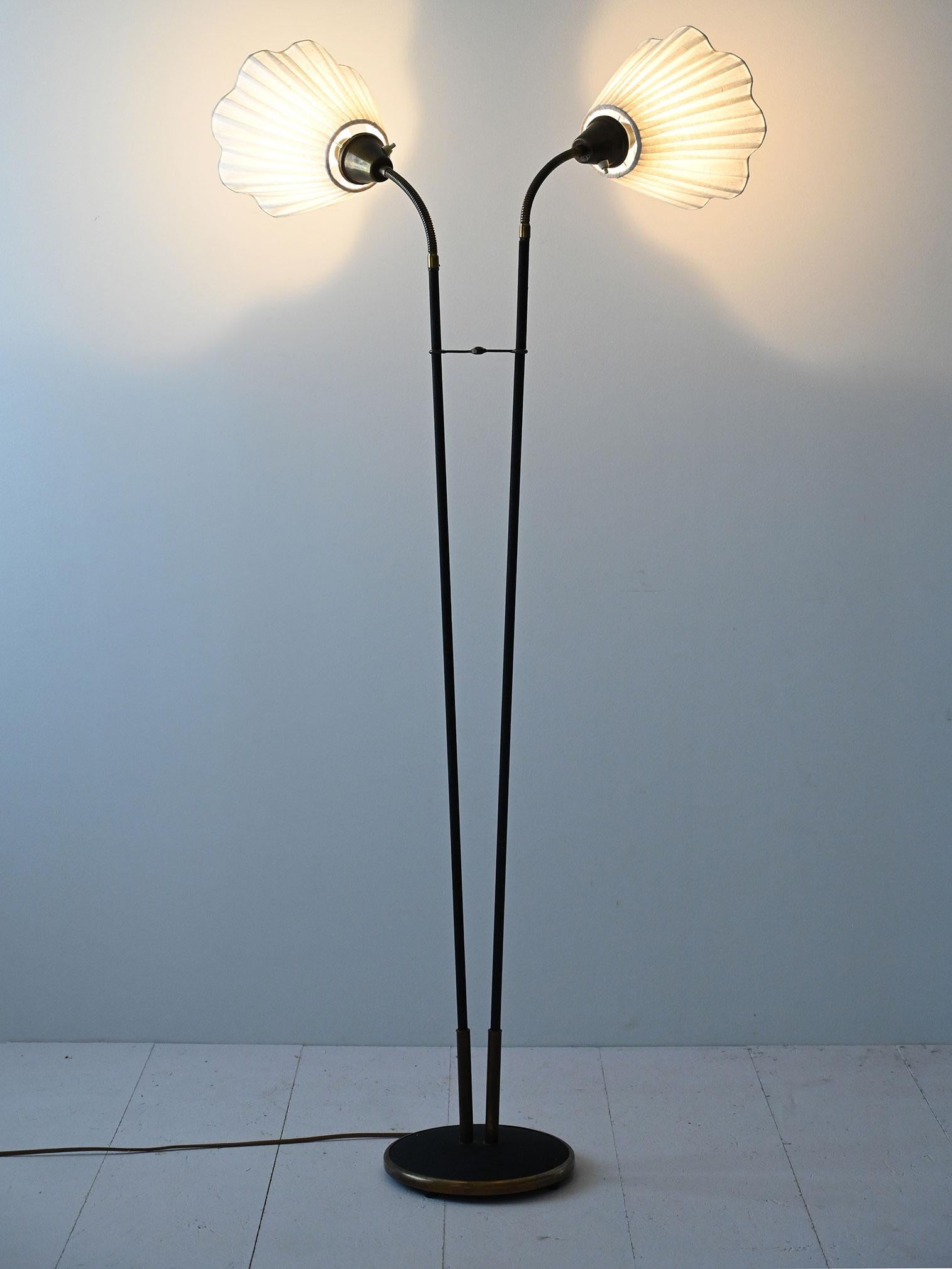 Vintage floor lamp, double pleated shade, elegant and functional design. Ideal for sophisticated and retro environments.

This lamp features two thin black rods that rise from a dark circular base, providing stability and a clean look. White,