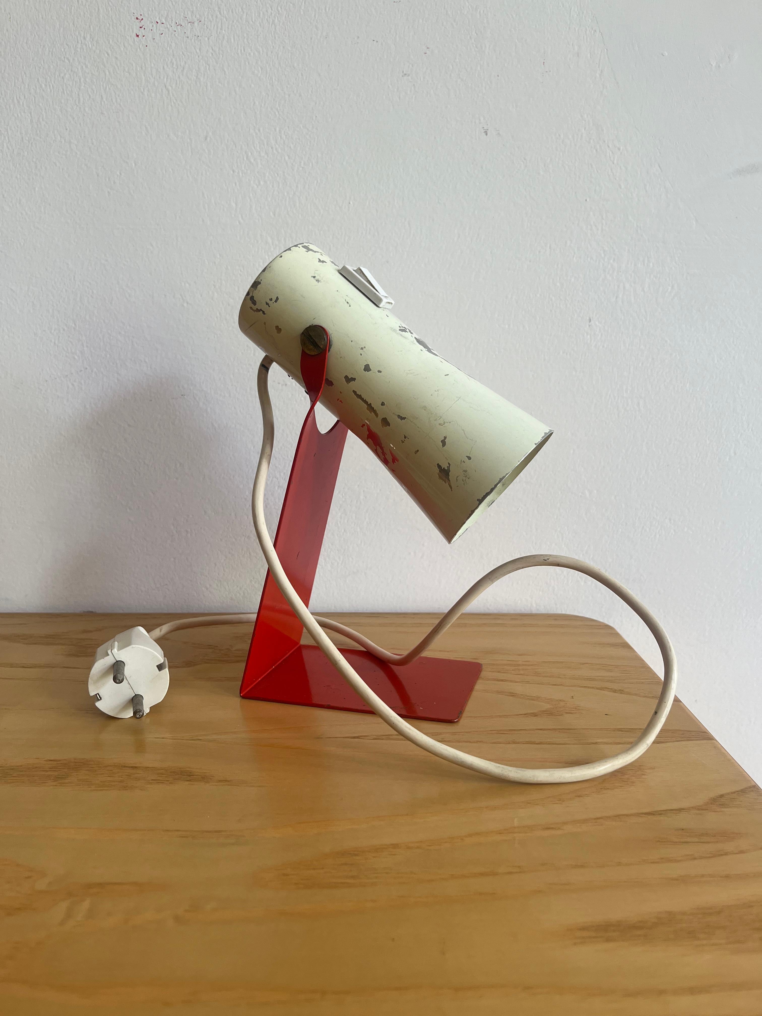 Small table lamp designed by Philips study center and produced by Philips in 1971.

The lamp is made of lacquered metal with a red base and white cap. As pictured has several discolorations and lack of color although the frame and mechanism are