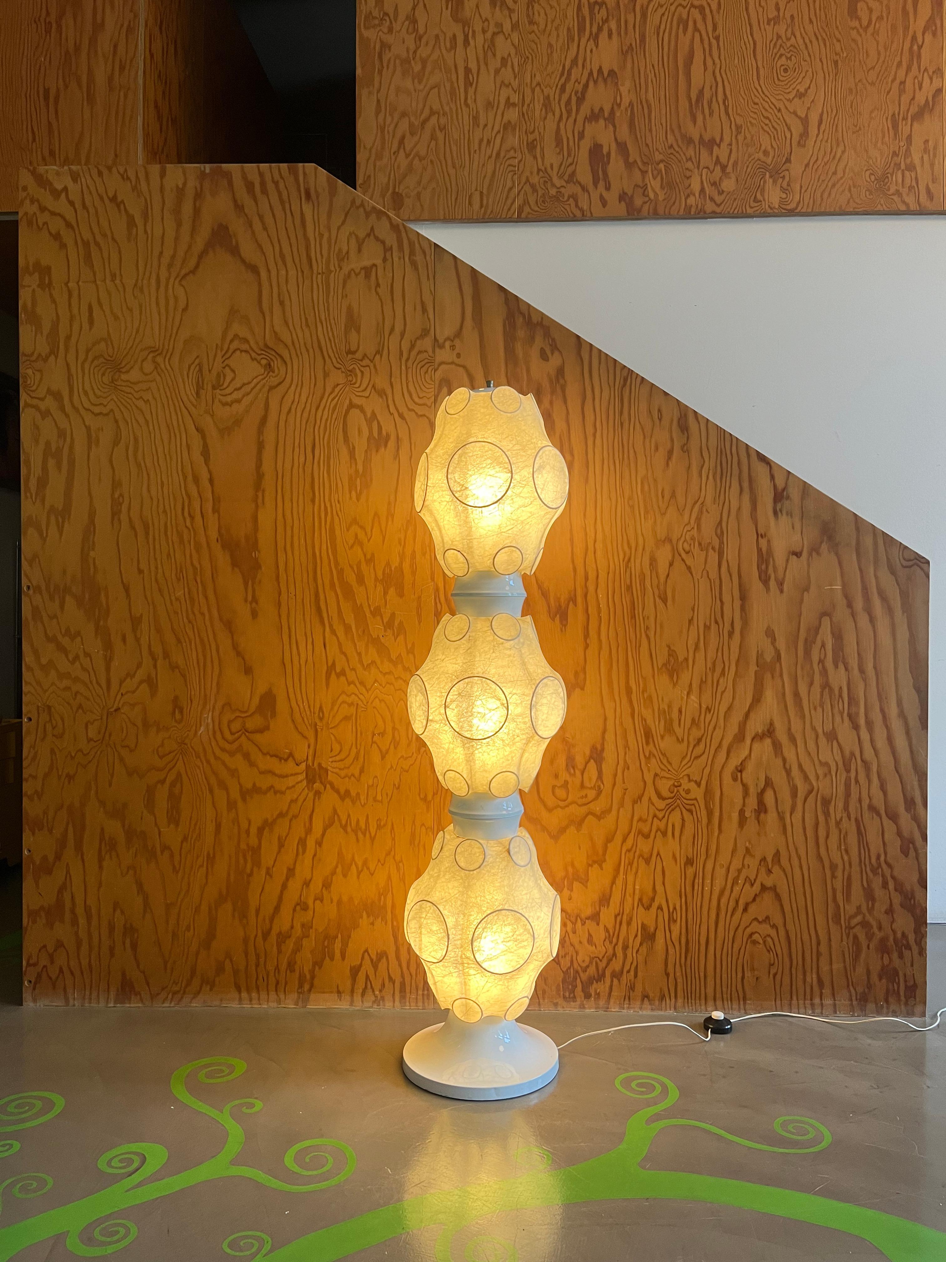 Floor lamp made of cocoon and metal presumably made by Flos in the 1960s, the time when the company was founded. 

The lamp consists of three cocoon lampshades on white metal bases all mounted on an invisible metal frame. 

It has two minor defects
