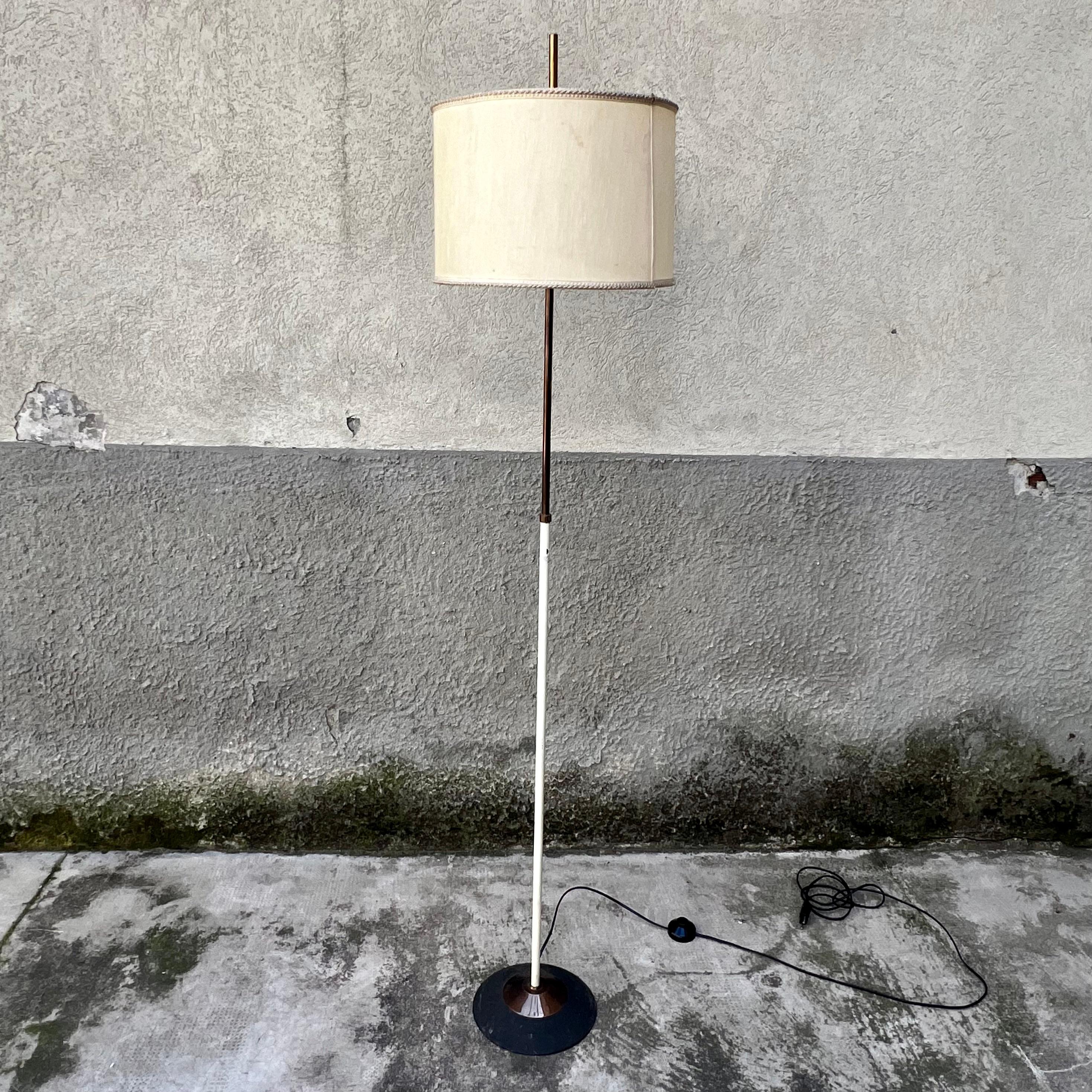 Lampada da terra in ottone e base conica in ghisa coperta da calotta in ottone. 
All'interno del suo paralume in tessuto, porta due lampadine E27.
Etichetta originale.
