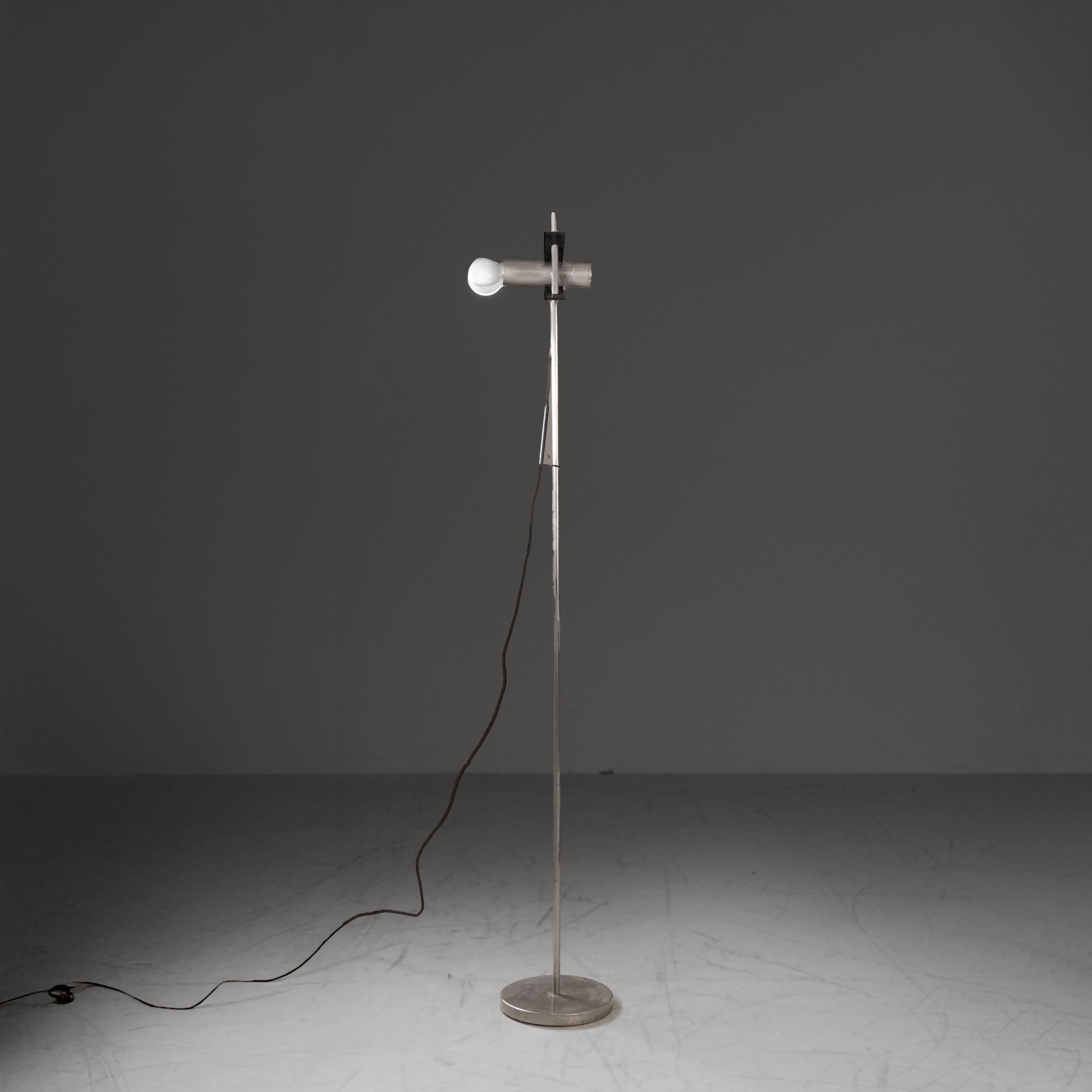 Disegnata da Angelo Ostuni per Oluce, la lampada da terra modello 399 è caratterizzata da una struttura in metallo nichelato, un corpo illuminante in metallo laccato tenuto fisso da una leva regolabile a pressione in bachelite e base in ghisa.