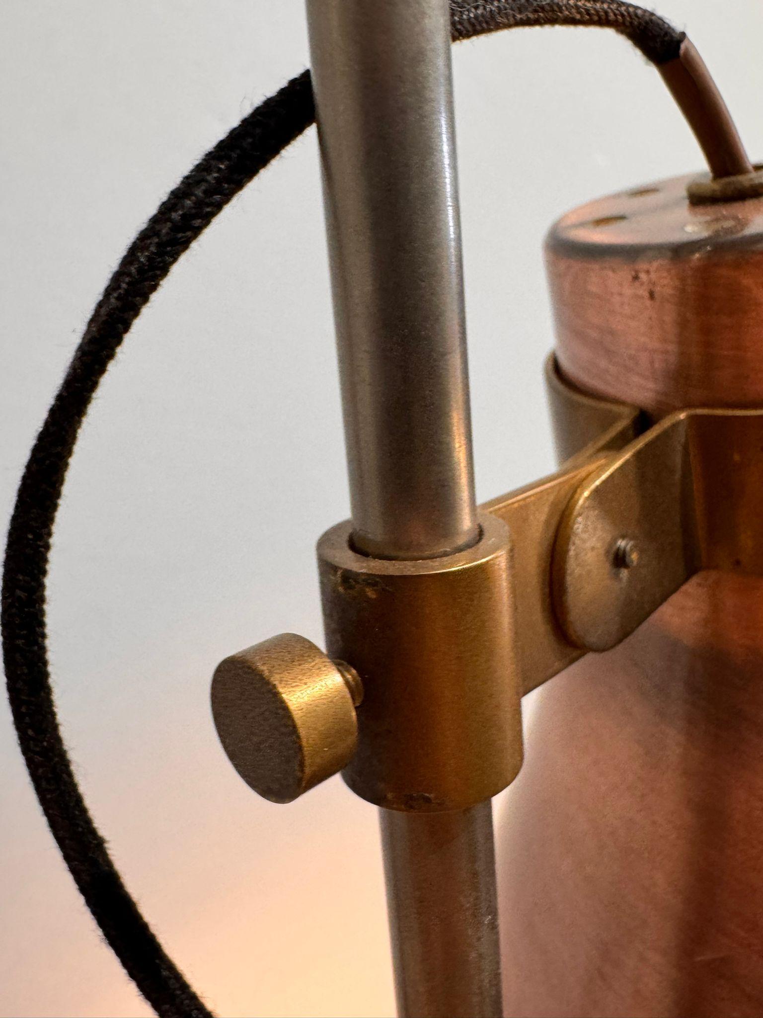 This 1950s-1960s floor lamp attributed to Luigi Caccia Dominioni is a fine example of mid-century Italian design with a slender sloping metal rod supporting two elegant conical copper-plated metal lampshades that can be oriented, creating a warm and