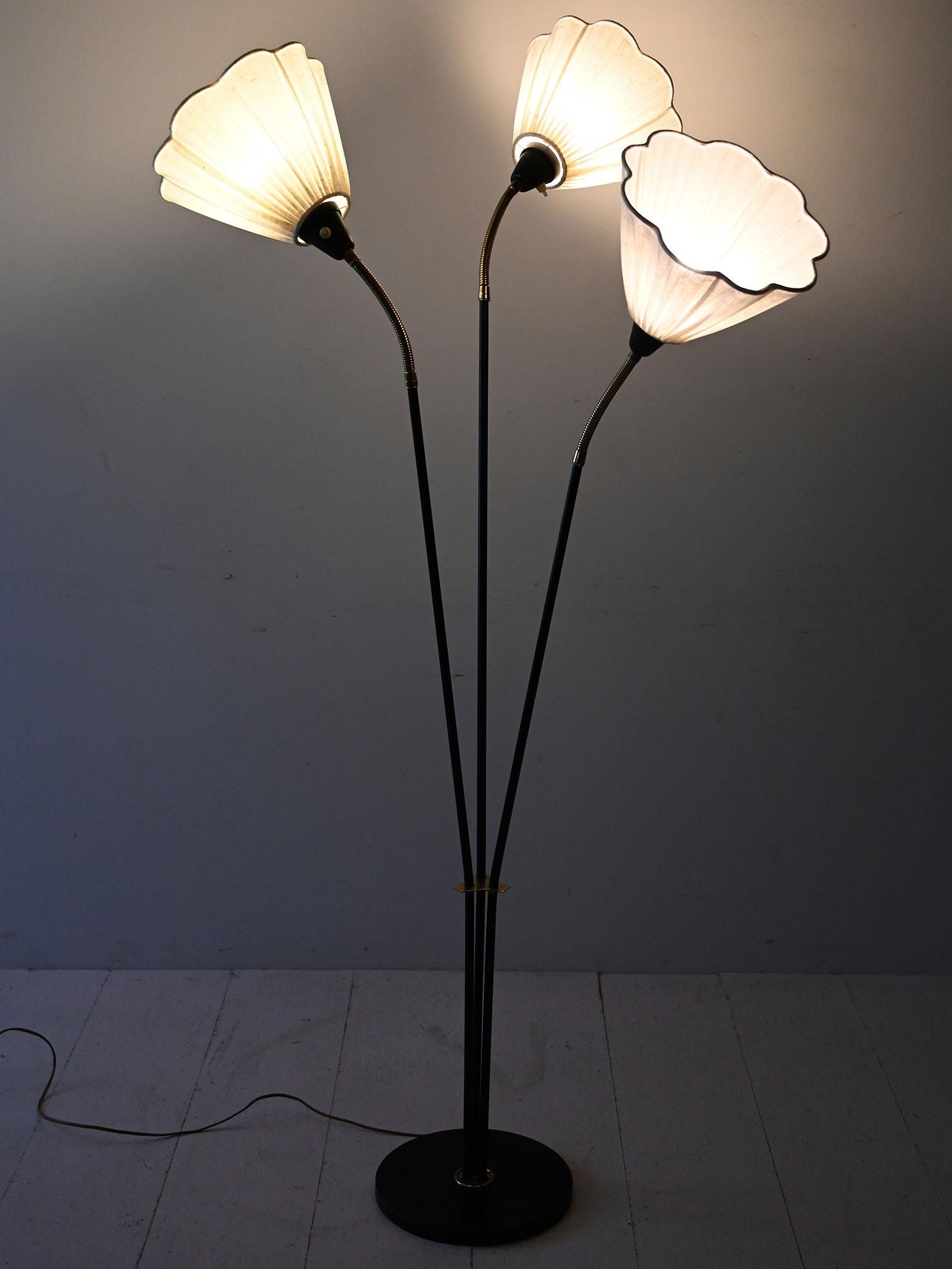 Lampada a tre bracci in metallo nero con dettagli in ottone e nuovi paralumi in tessuto plissettato chiaro.

Lampada da terra di produzione scandinava anni ’50 con struttura in metallo nero e dettagli in ottone. I tre bracci, snodabili alla base del