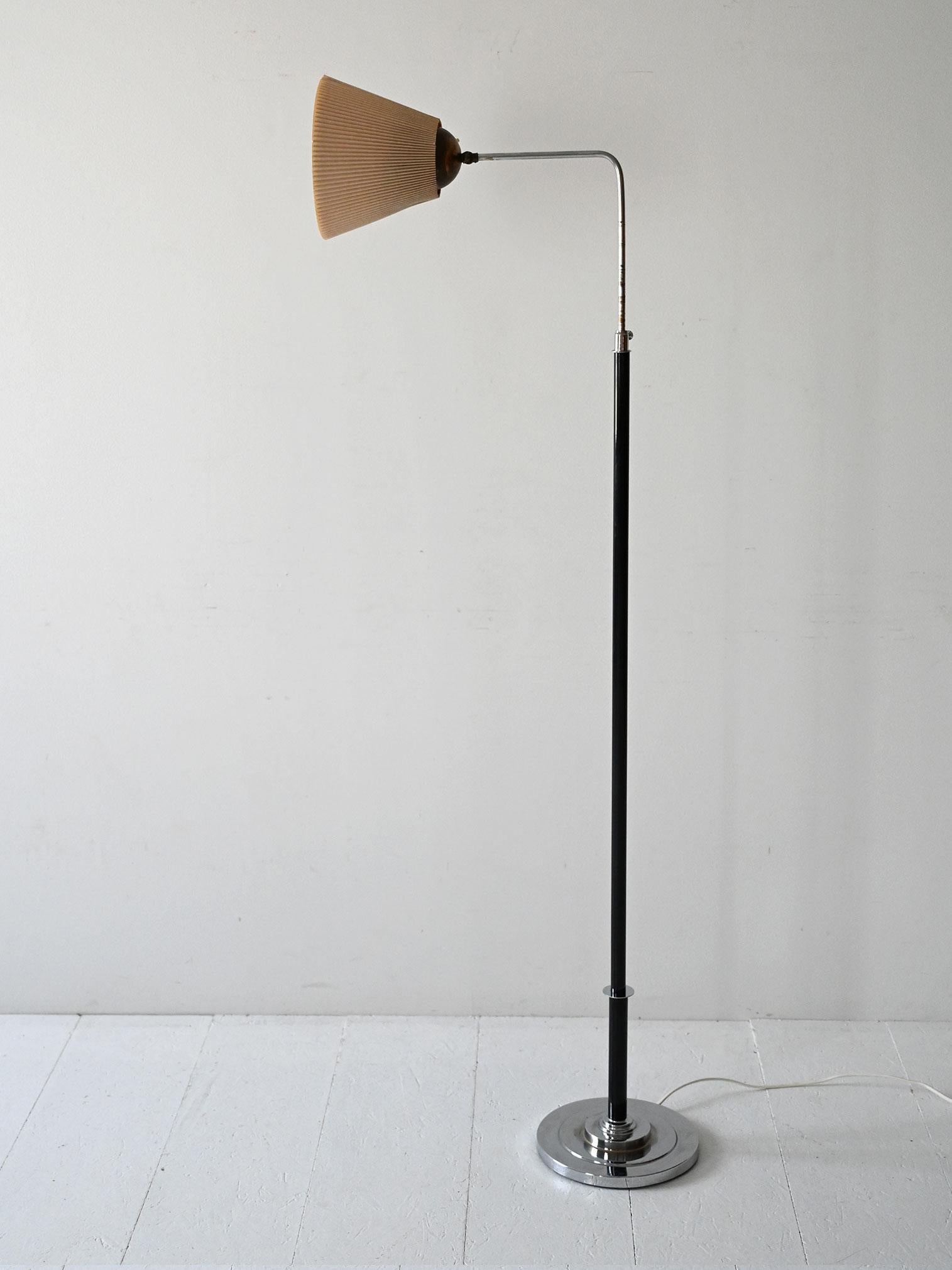 Lampada svedese anni ’30 con base cromata, stelo nero e paralume plissettato orientabile in tessuto beige.

Realizzata negli anni ’30 in pieno stile Funkis, questa lampada da terra unisce funzionalità e rigore formale. La base è in acciaio cromato,