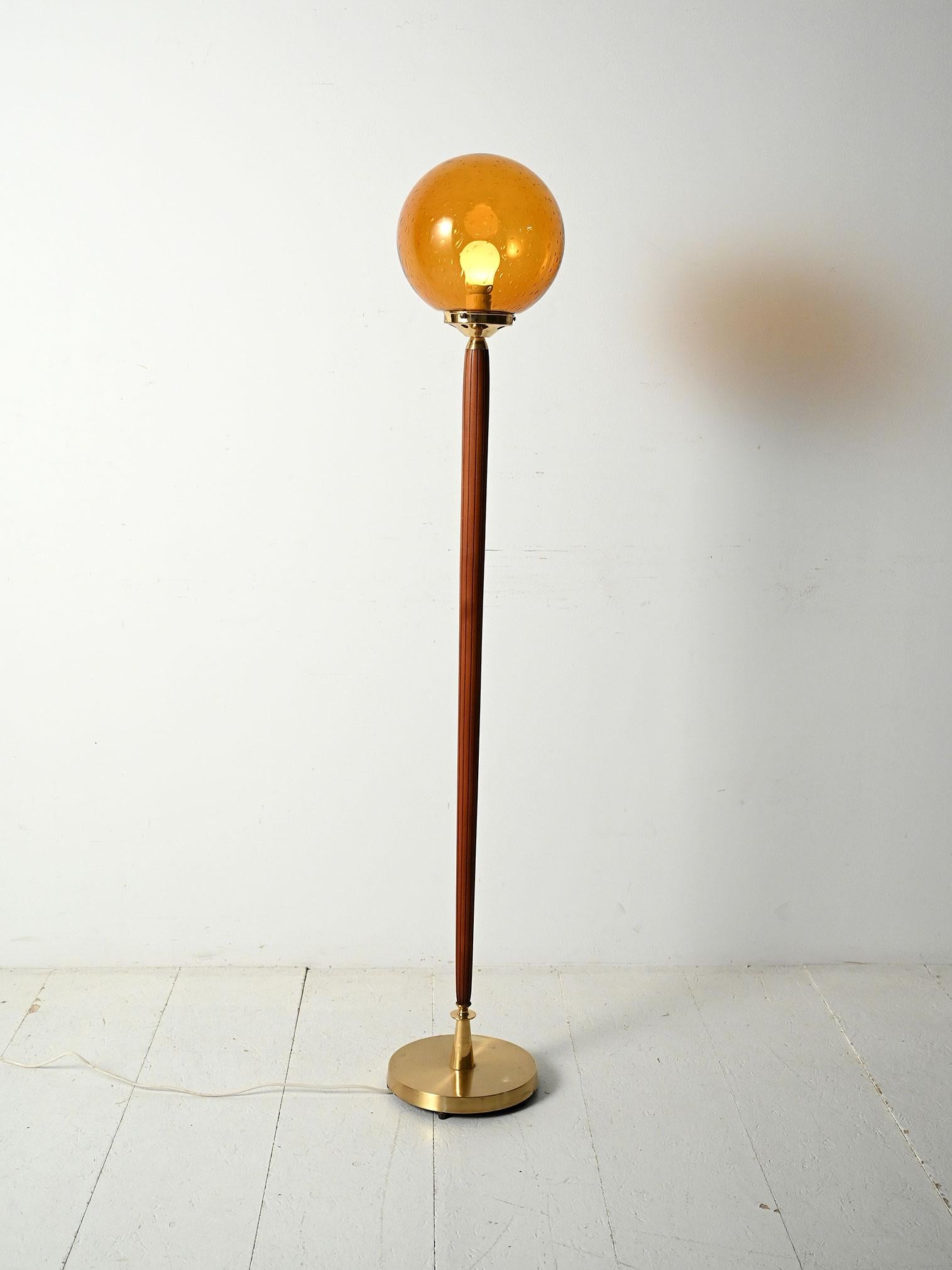 Lampada da terra scandinava anni '60 con stelo in teak, base in ottone e globo in vetro color ambra soffiato.

Elegante Lampe aus Skandinavien aus den 60er Jahren, mit einem Ständer aus Teakholz, einem Sockel aus Ottone und einer Kugel aus