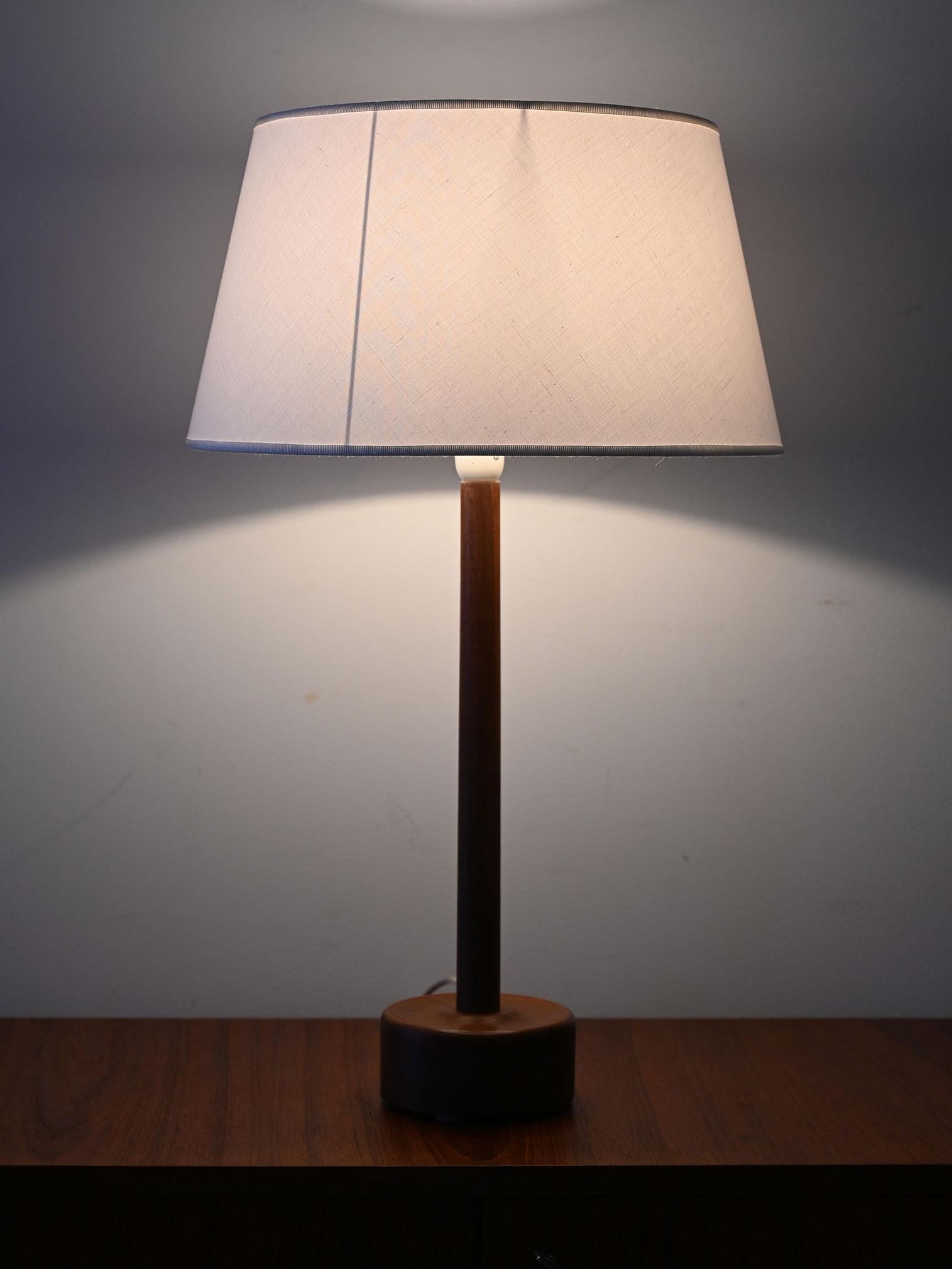 Lampada da tavolo in teak con paralume in tessuto. Design danese anni ’50/’60, paralume restaurato.

Lampada da tavolo di design danese realizzata negli anni ’50/’60, con base in teak tornito e paralume in tessuto chiaro. Le linee essenziali e la