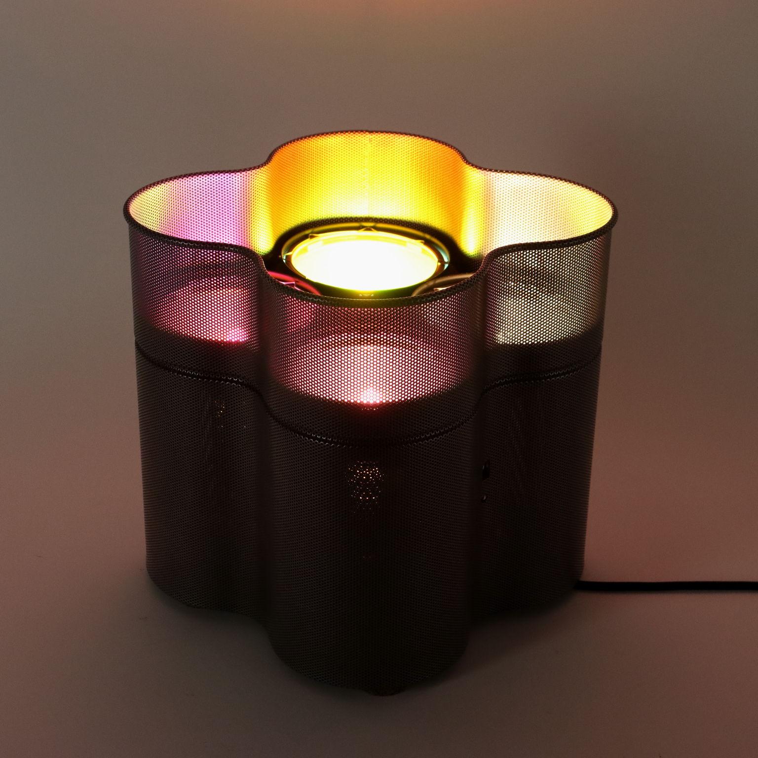 Lampada in acciaio traforato smaltato. Orientabile su due lati, con 4 fari da 150W con filtri rosso, giallo, blu, neutro. Telecomando con regolatore luce elettronico.
