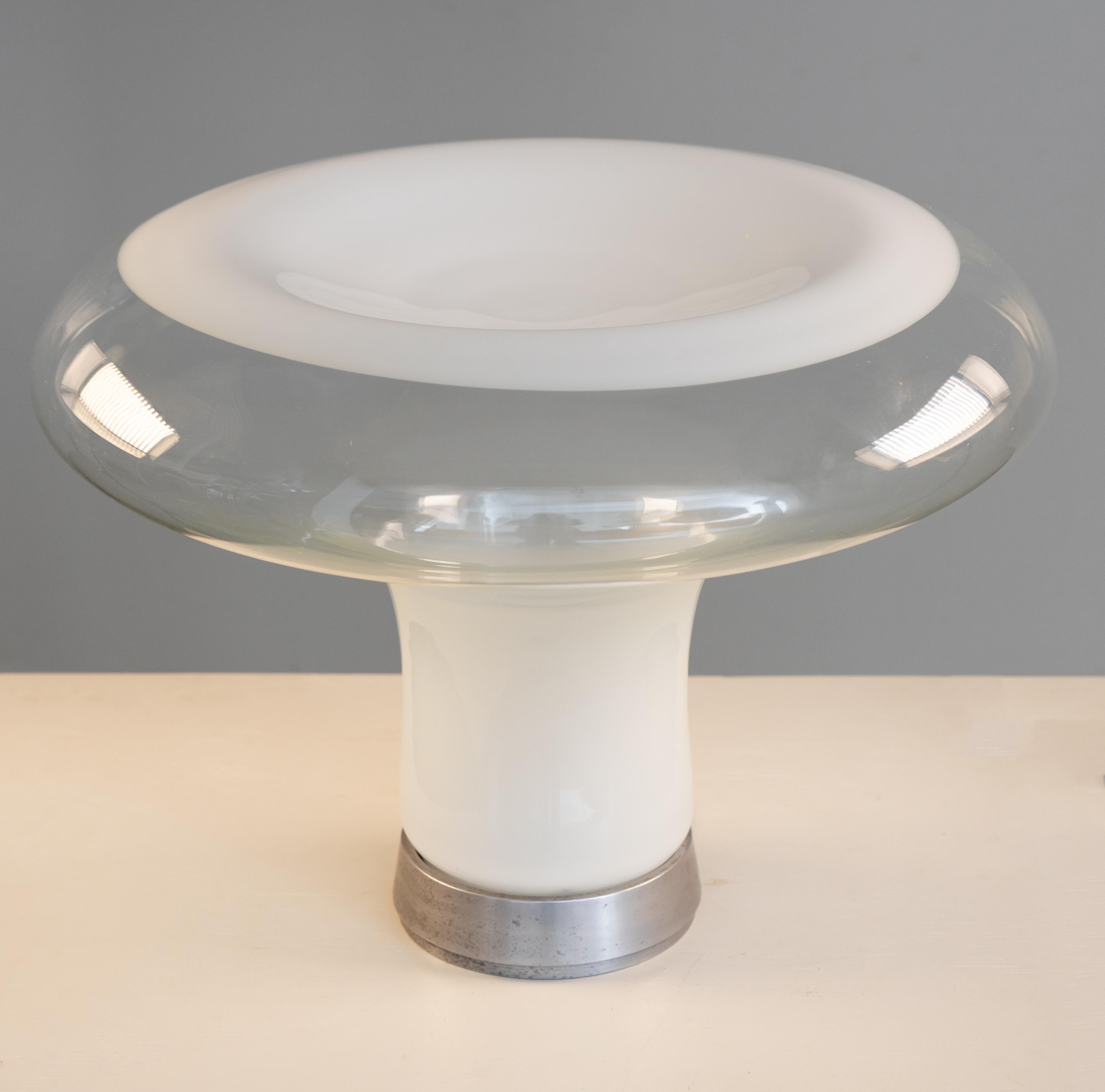 Lampada Lesbo, disegnata da Angelo Mangiarotti per Artemide nel 1967. Diffusore in vetro soffiato a mano, che interagisce con la luce in modo raffinato: la sfumatura del bianco nasconde la sorgente luminosa, indirizzando l’emissione verso l’alto e