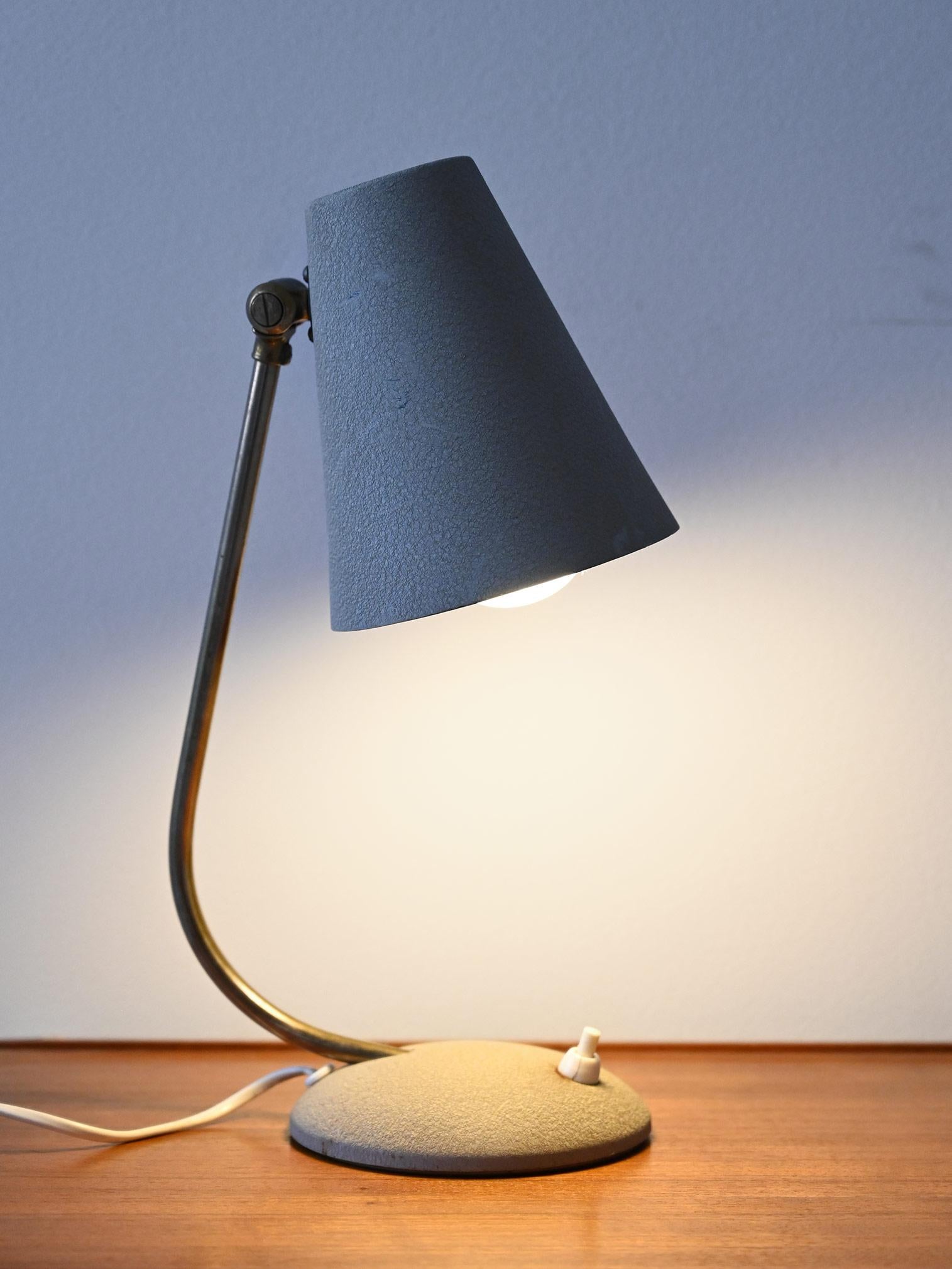 Swedish desk lamp from the 1950s, produced by the EWA company. It features a sleek, minimalist design with a metal and brass frame. The adjustable lampshade lends functionality and flexibility, making it a versatile addition to any workspace.

This