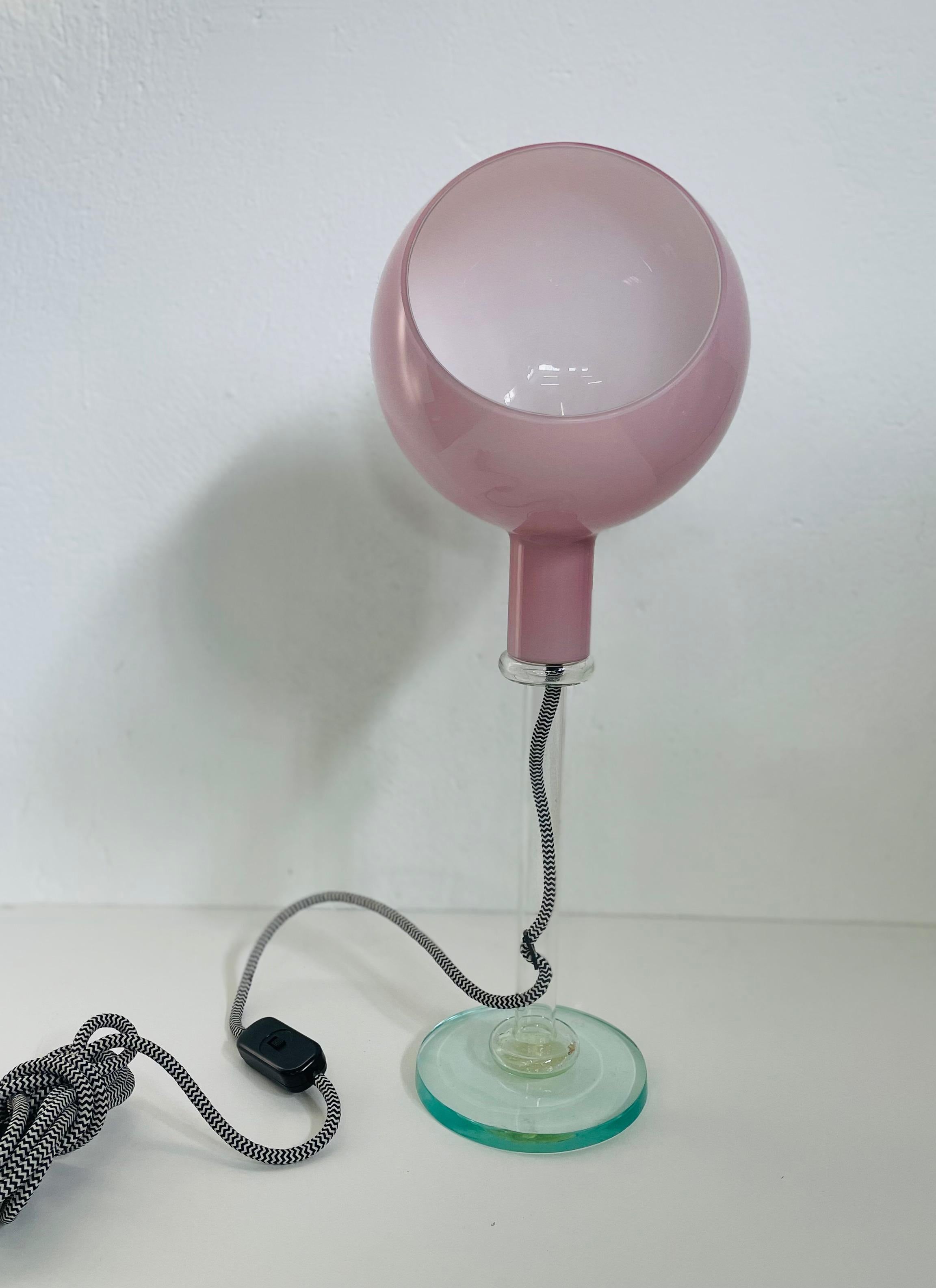 Lampada da tavolo 'Parola' di Gae Aulenti & Piero Castiglioni in bianco per Fontana Arte.

Progettata per la prima volta nel 1980, la Parola presenta tre diversi tipi di lavorazione del vetro: vetro soffiato opalino per il paralume, vetro naturale
