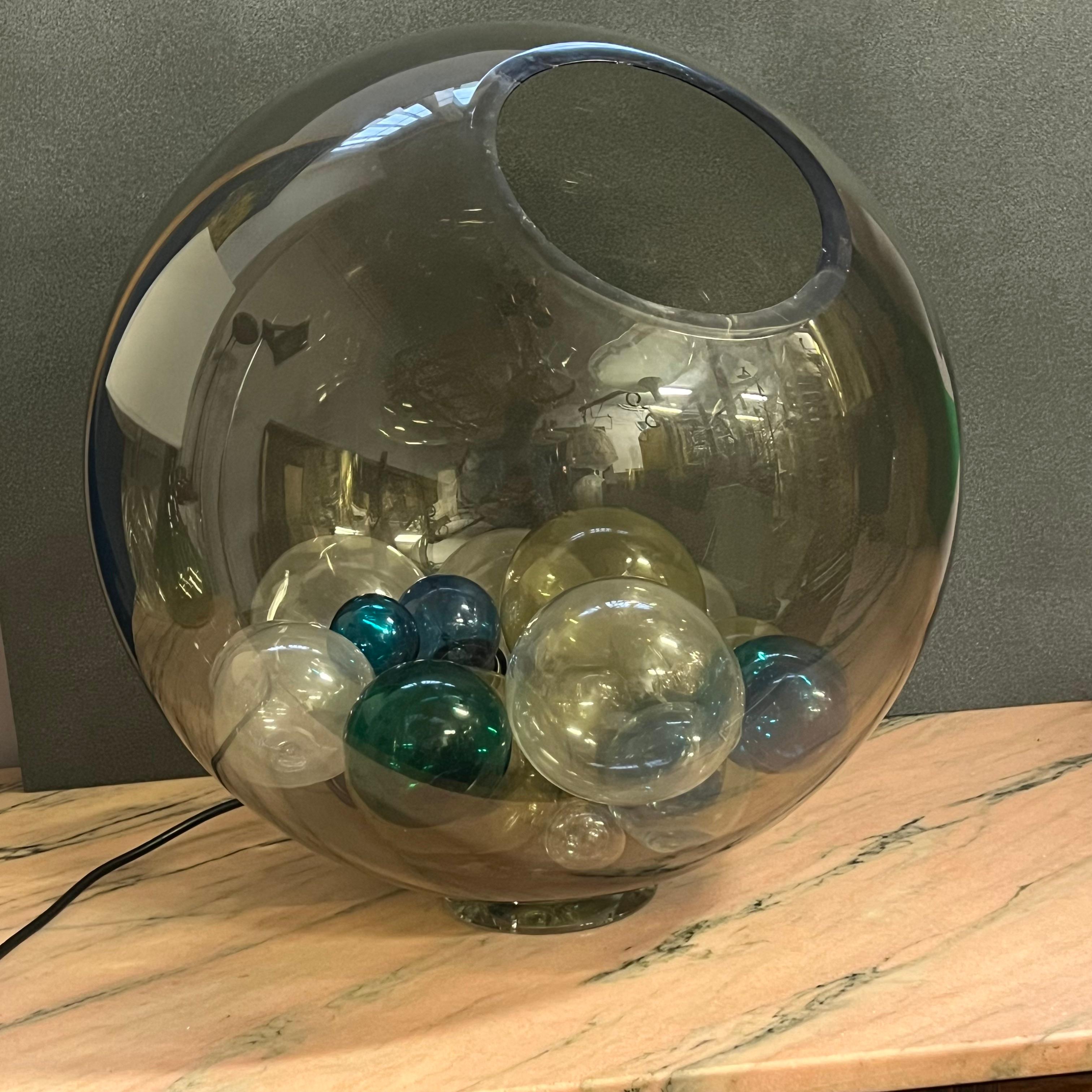Esta extraordinaria lámpara de mesa, modelo Pallotta, es un raro ejemplo de la excelencia artesanal de Venini, famoso fabricante de Murano. 
Fabricada en la década de 1960, la lámpara presenta un gran globo de vidrio soplado ahumado transparente, en
