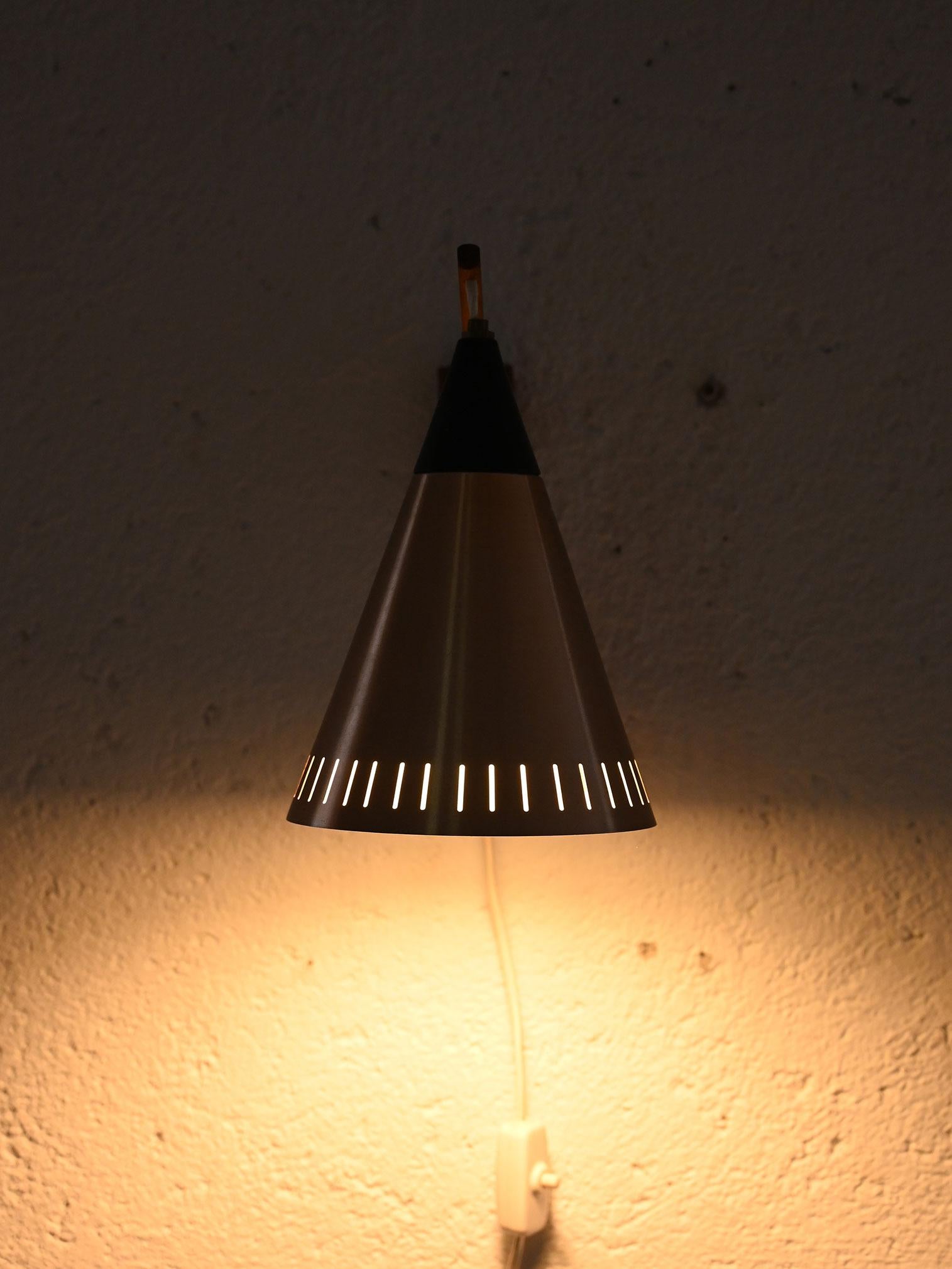 Vintage wall sconce with wooden arm and lampshade made of sheet metal and black plastic. 

A lamp that, thanks to the conical shape of the shade and decorative openings on the edge, recreates a soft light. 
Good conditions. The electrical system is