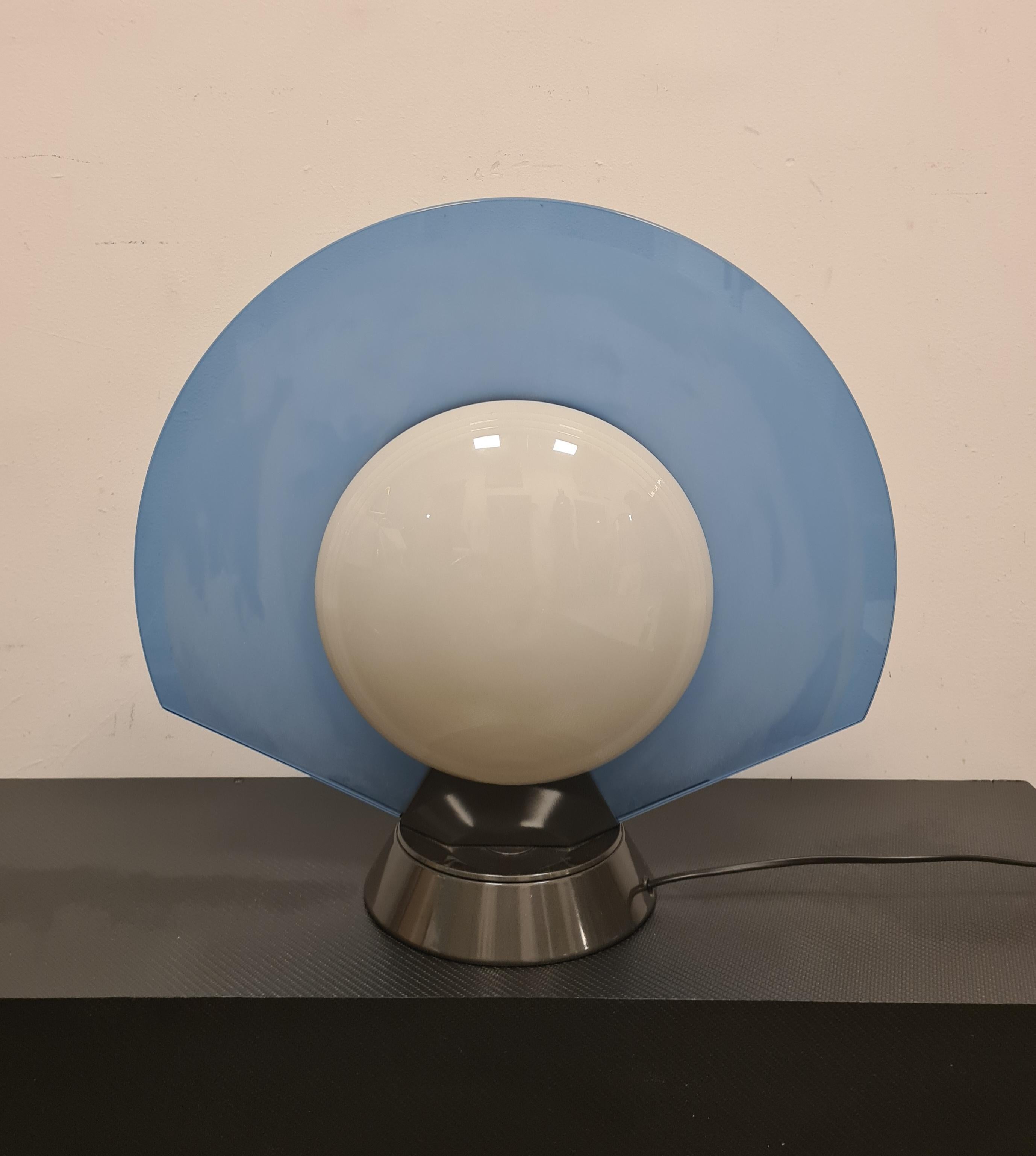 Table lamp model Tikal 1555 designed by Pier Giuseppe Ramella for Arteluce.

Elegant table lamp model Tikal 1555, the name and shape recall the Mayan culture.

The lamp has a swivel lacquered metal base on which rests a blue glass on one side