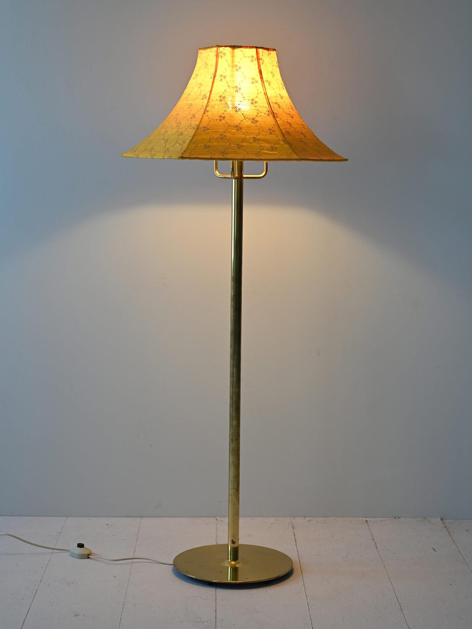 Ce lampadaire vintage est doté d'une tige et d'une base ronde en métal doré, ce qui lui confère une touche de luxe et de sophistication. Le métal doré, avec sa finition brillante, reflète la lumière, créant un effet chaleureux et