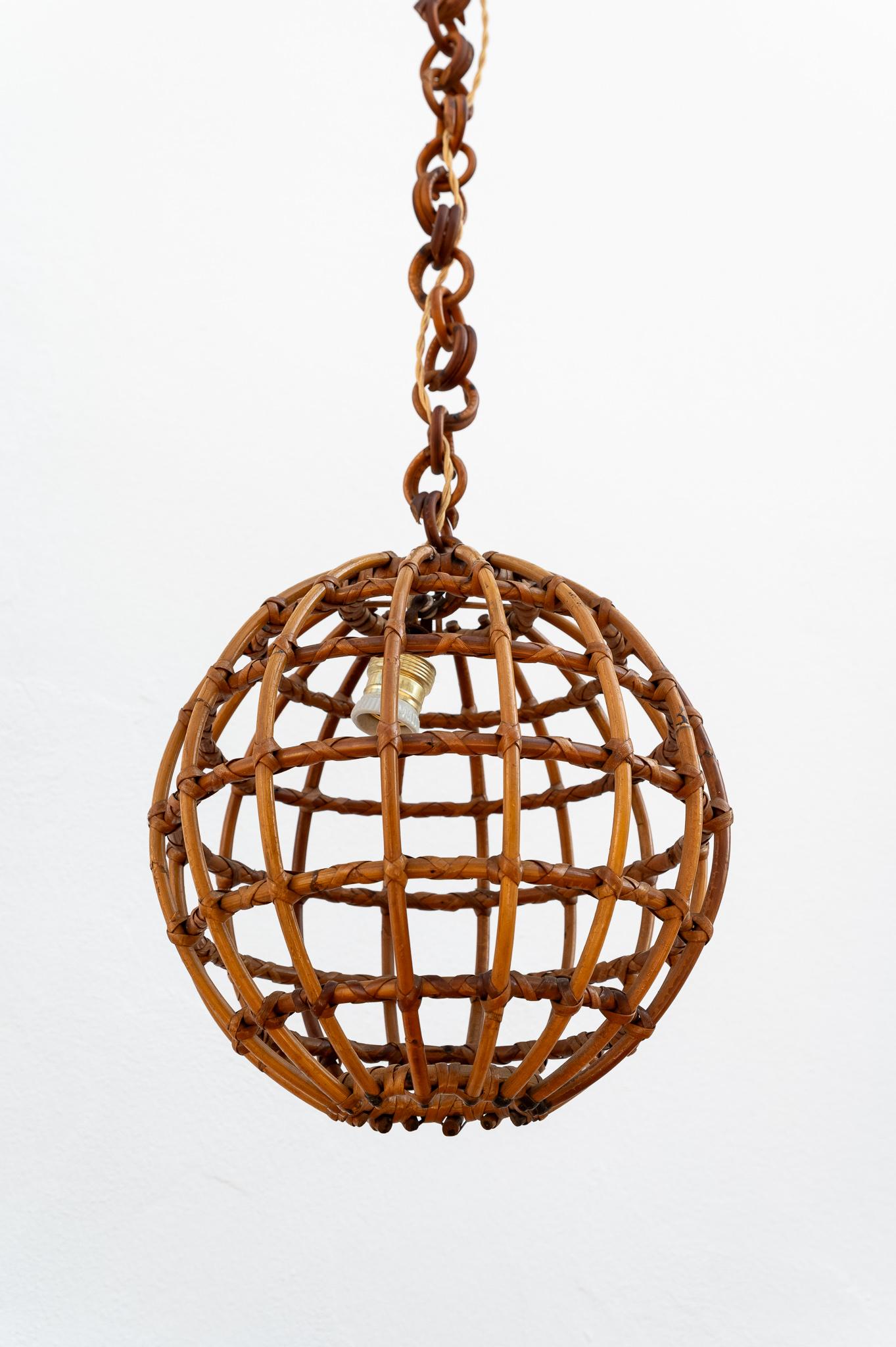 Rattan globe chandelier, 1960s, Made in Italy.
Rattan globe-shaped ceiling chandelier, 1960s. This particular chandelier features a spherical lampshade made of rattan reeds. Hanging from a wicker-link chain, topped with a rattan stud. The length of