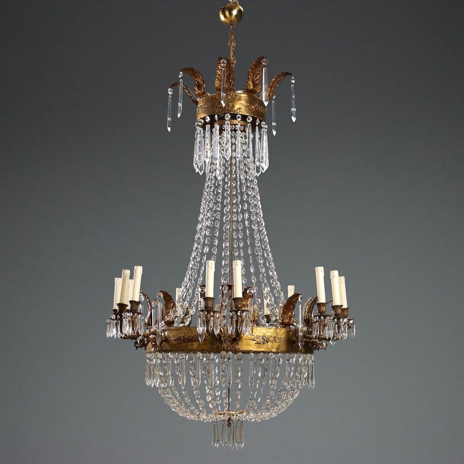 Lampadario a mongolfiera in metallo e lamierino lavorato a sbalzo e dorato. Decori del lamierino che accennano al futuro gusto Liberty. Quattordici luci disposte a coppie, pendenti e collane in vetro.
Italia, ultimo quarto XIX Secolo.	