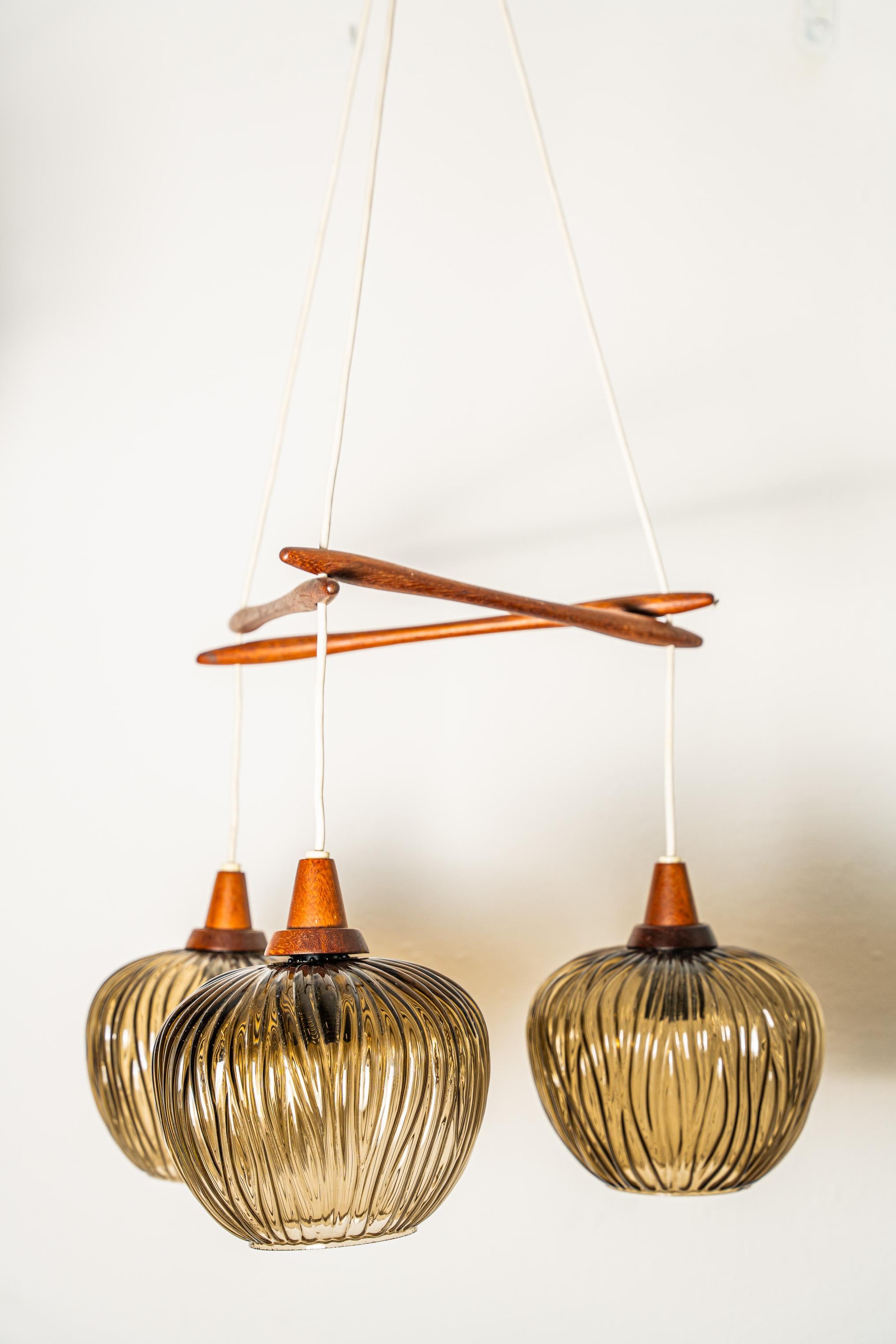 Three-light pendant chandelier. The frame consists of three finely turned wooden supports, as wooden are the lamp holder supports; the lampshades are made of honey-green murano glass
The chandelier, made in Italy in the 1950s, can be attributed to
