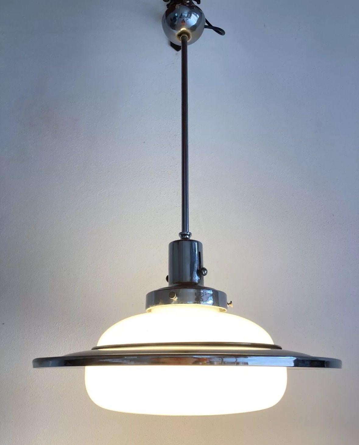Large rationalist 1940s chandelier lamp made of chrome-plated brass and white opaline glass, with one light point, working.
The chandelier has a diameter of 54 cm, and the height including the upper rod is 70-90 cm due to its elongating qualities
