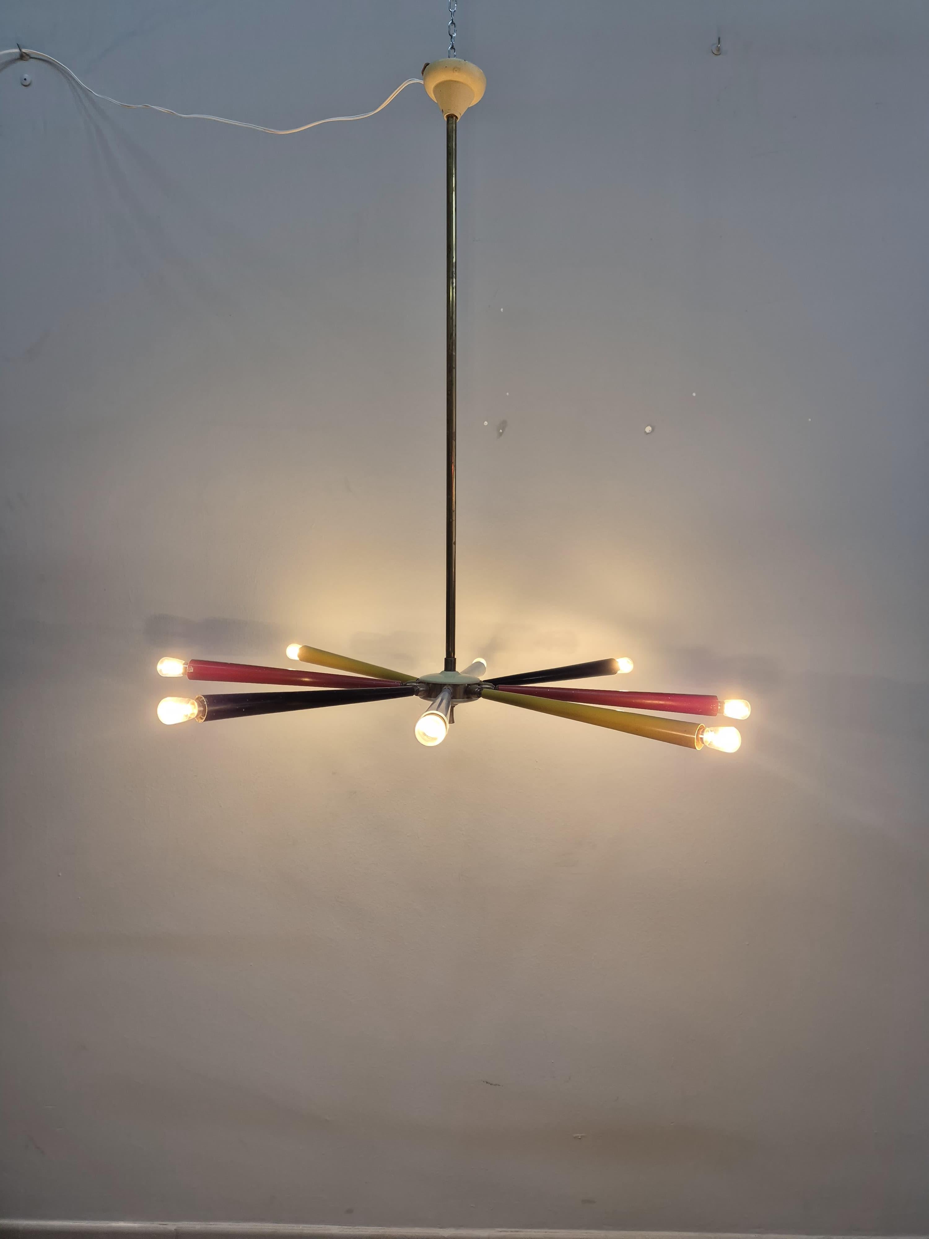 Lampadario anni '50 colorato nello stile di Stilnovo. Il lampadario ha otto braccia, in quattro colori differenti, direzionabili verso l'alto o verso il basso a proprio piacimento. La struttura è in metallo e la coppetta in plastica.
