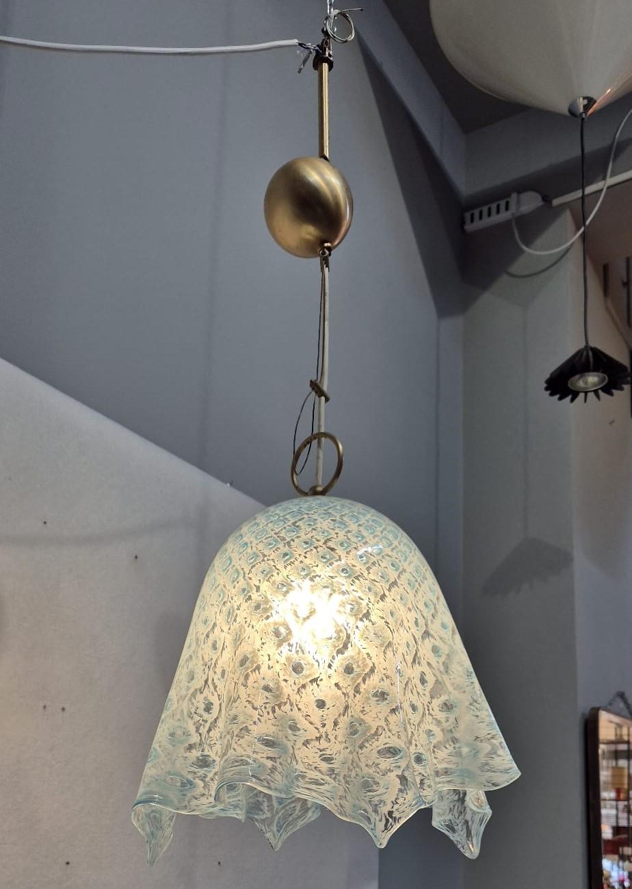 Lampadario anni '60 La Murrina, in vetro di Murano. Il lampadario ha la forma di una campana con la base ondulata. Il vetro è trasparente con dei motivi azzurri e ha una struttura in metallo. Il lampadario presenta un unico punto luce, ma risulta