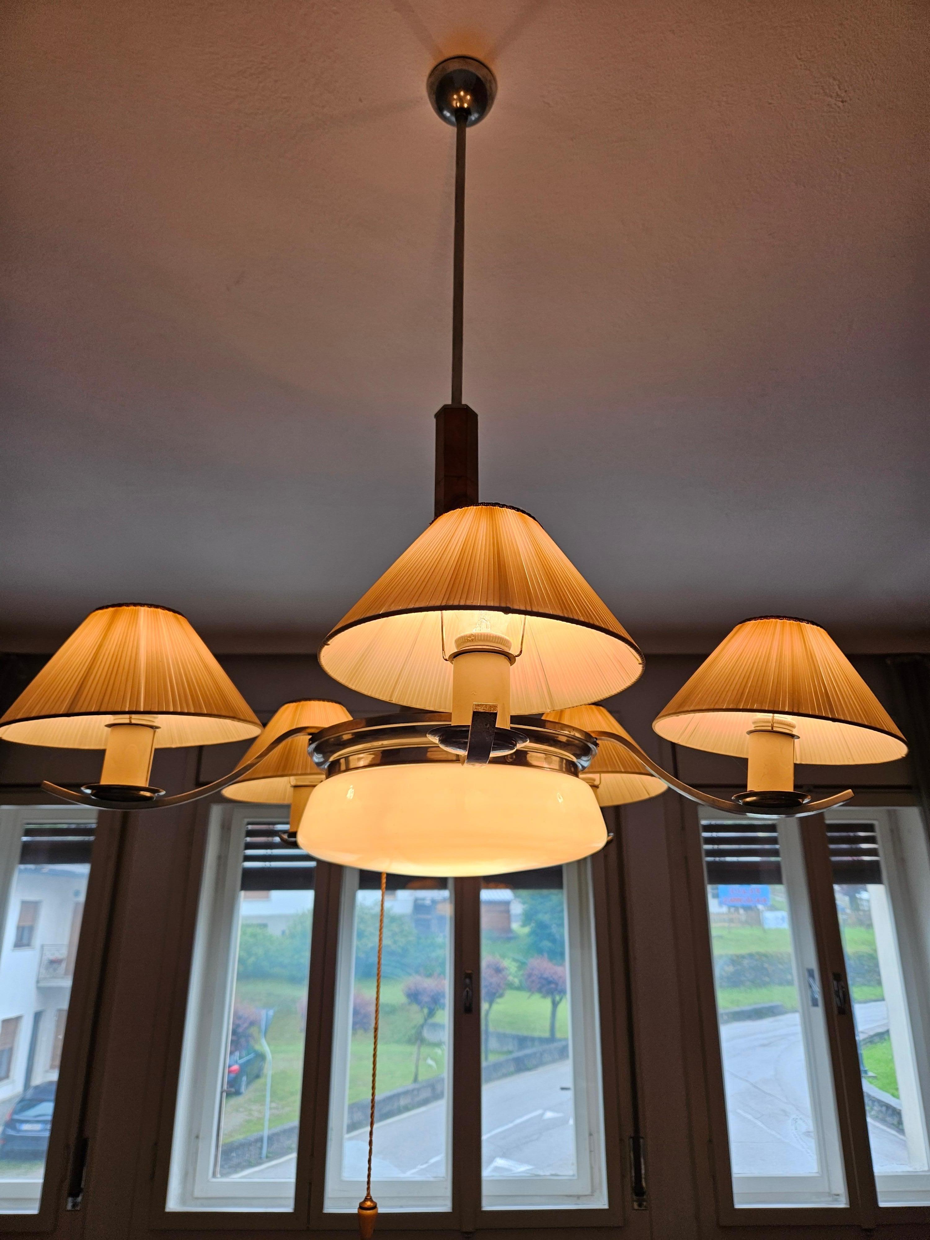 Gran lámpara italiana de la época Art Decó con estructura de acrílico decorada con un revestimiento de radios de madera y paralúmenes de cartón esponjoso.

Destaca la armonía de los brazos de acero que separan los puntos de luz y el diseño de la