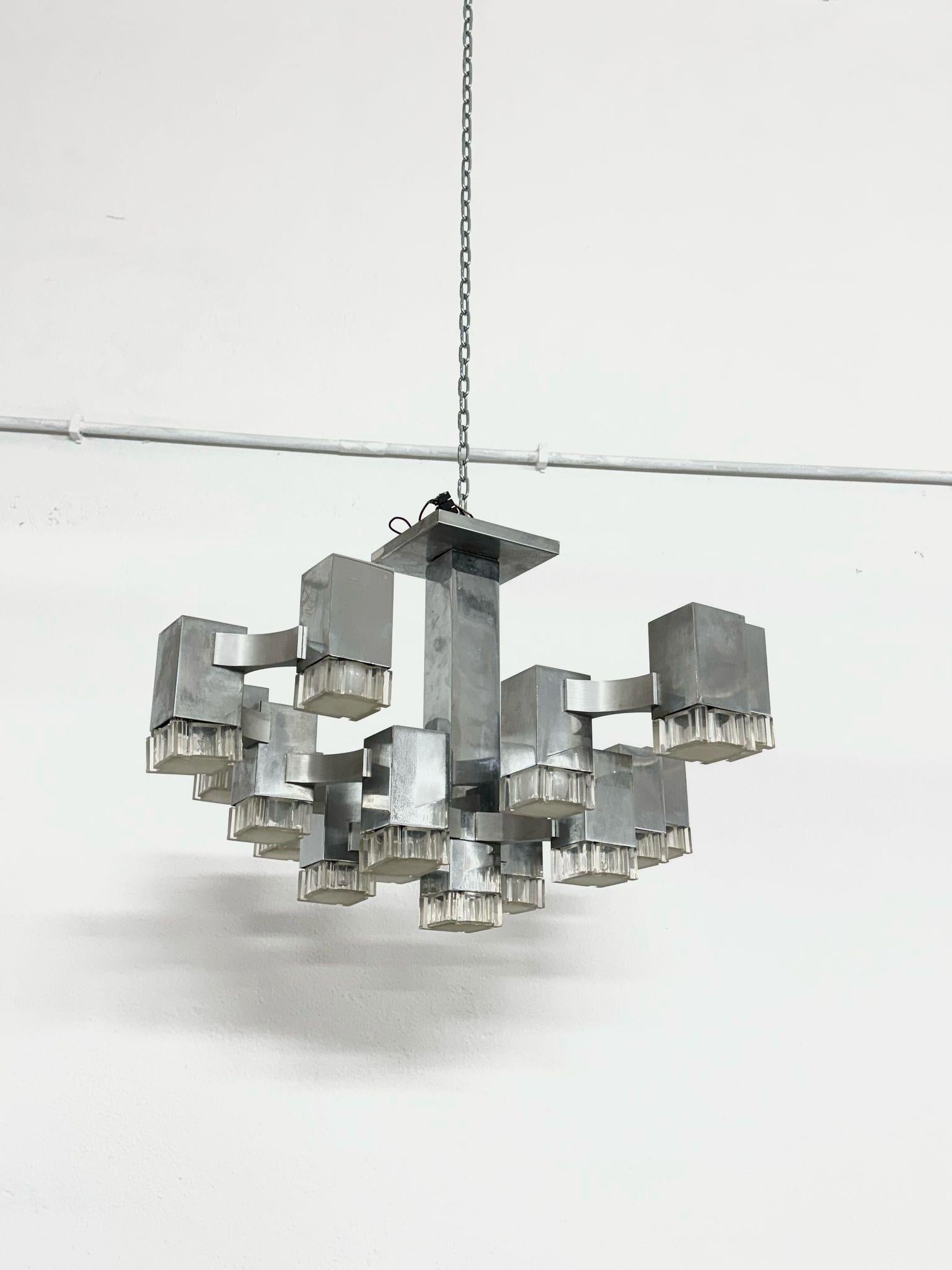 Beautiful silver-colored cubic lampstand by Gaetano Sciolari 1970s. The chandelier consists of 17 lights, the frame is made of metal, and the 17 bulbs are housed in a cubic plexiglass frame.
The design of this particular chandelier was inspired