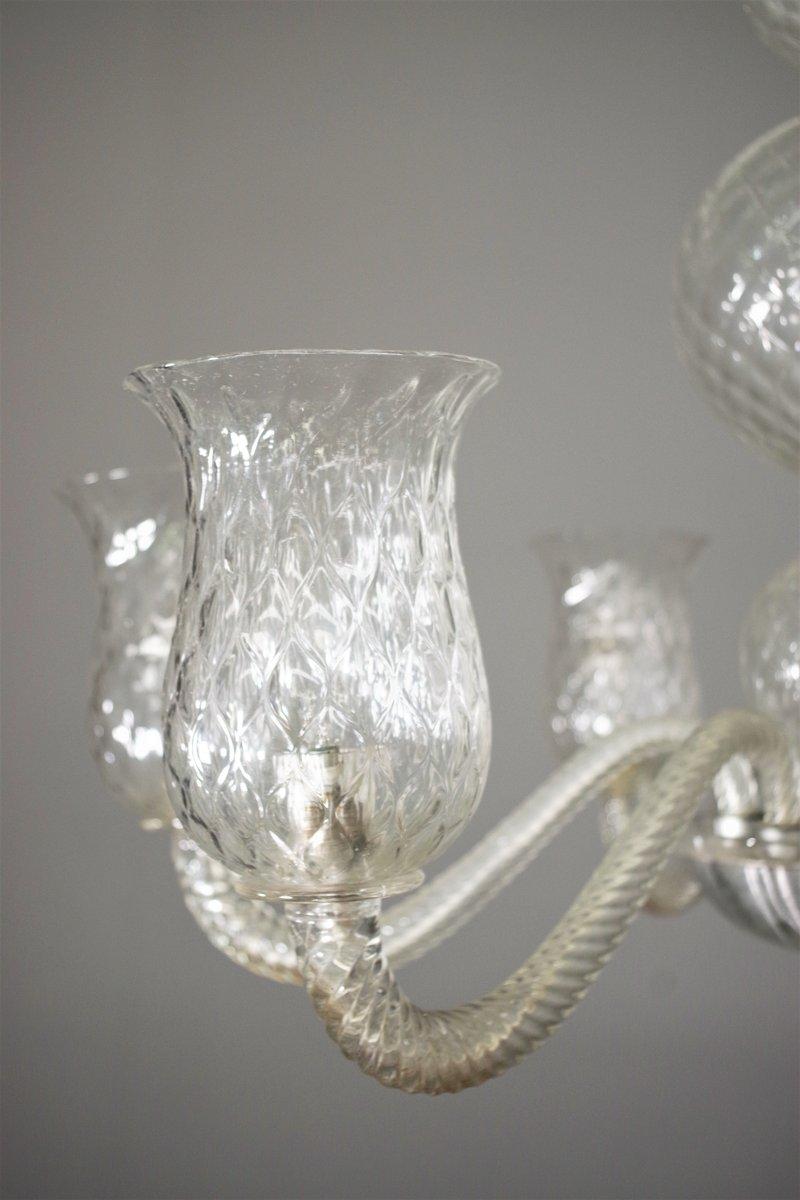 Auténtica araña Venini de fino cristal de Murano soplado a mano, de los años 50. Esta exquisita pieza de diseño vintage encarna la elegancia italiana de mediados del siglo XX, con una artesanía de la más alta calidad.

Con seis brazos sinuosos de