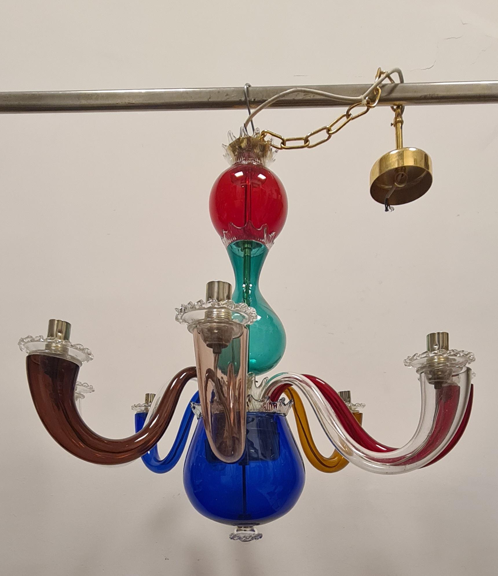 Maestoso lampadario disegnato da Gio Ponti per Venini.

Lampadario a otto braccia in vetro trasparente policromo e scheletro in ottone, fu' realizzato negli anni 70' su disegno di Gio Ponti del 1946.

Il lampadario presenta sulla boccia blu la