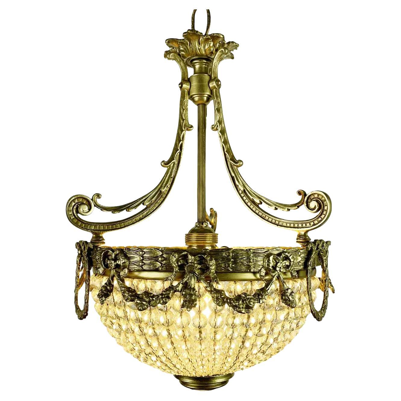 Early 1900s French Bronze And Crystal Entrance Chandelier with the reflective body composed of an inverted dome of English pearls with a sloping diameter. The frame of this Empire-style suspension is made of cast gilt bronze with a circular leafy
