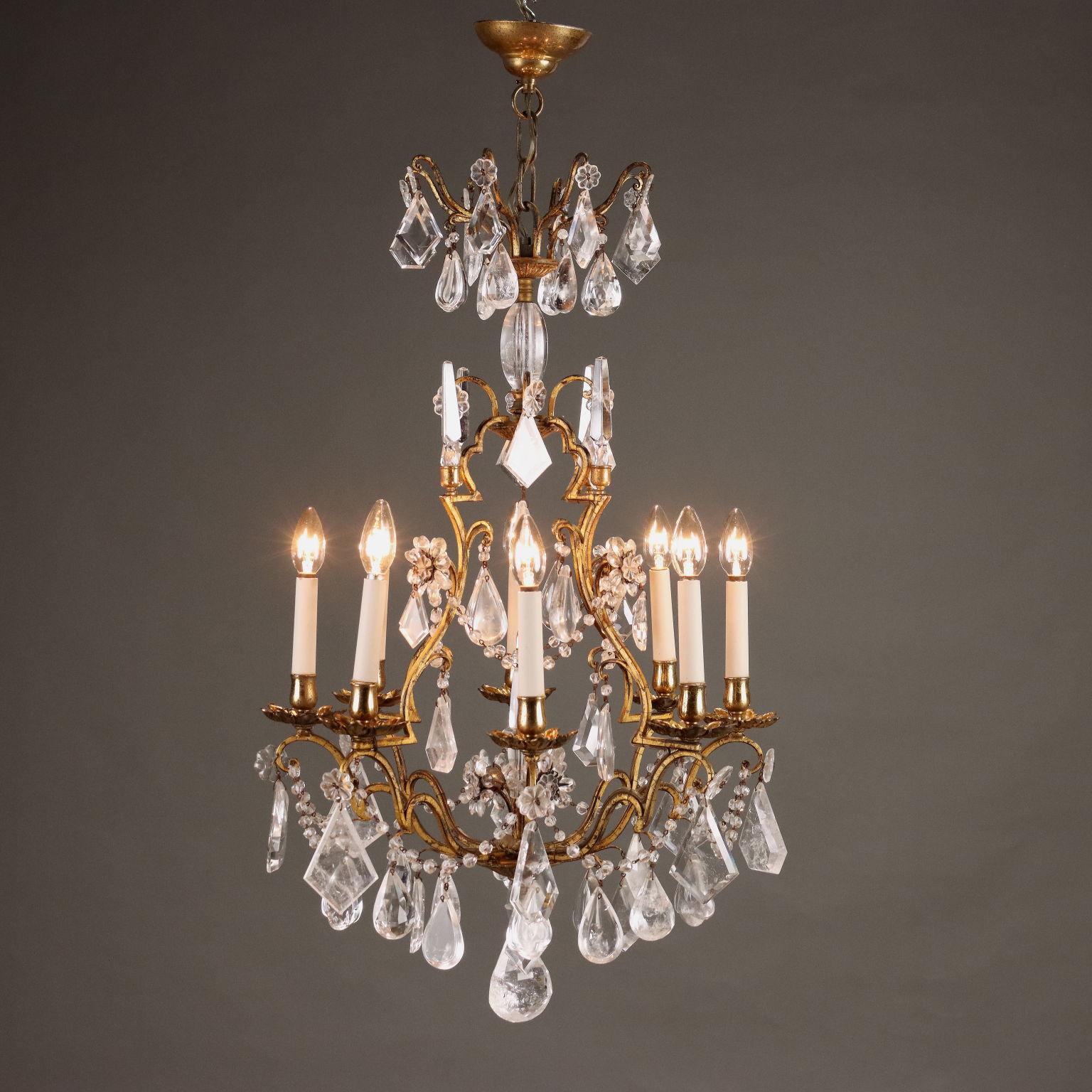 Lampadario in ferro battuto dorato a otto luci, bobeches a fiore e porta candele in bronzo dorato, collane, pendenti, fiori e puntali in cristallo di rocca finemente lavorato.
Italia, fine XIX Secolo.