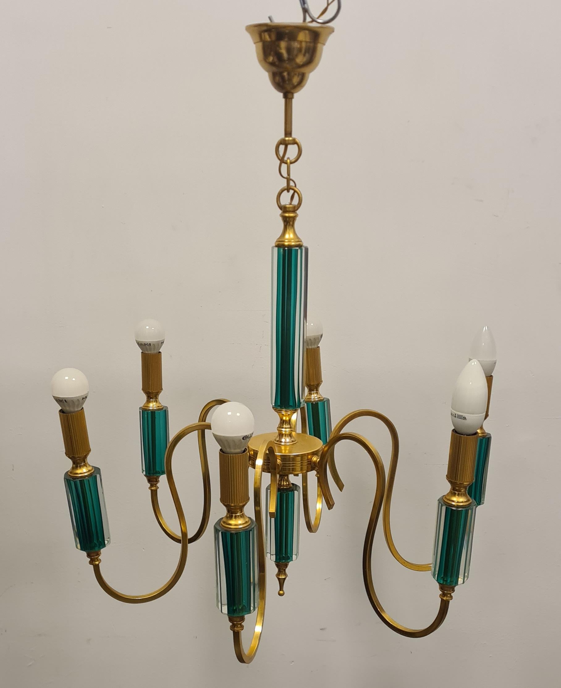 Six-light gold metal and glass chandelier.

Refined chandelier made with a golden metal frame and green-colored submerged glass decorations.

Elegant and extremely decorative this chandelier will add a touch of class to your rooms.

Ideal for