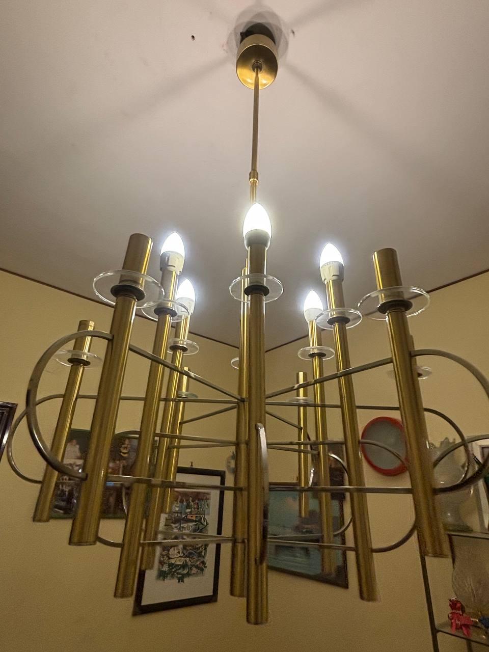 Lampadario scultoreo  dalle linee pulite in ottone e nichel con dischi di vetro trasparente all'interno della porta lampade removibili per sistemare la tua lampadina al meglio. Abbiamo  come si puo' ben notare dal video e dalle foto elencate 12 luci