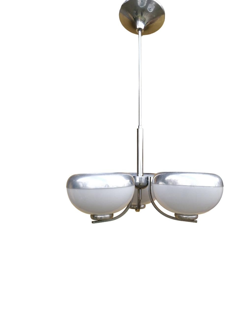 Ia lampada a sospesione con tre semisfere in vetro bianco ed alluminio, con la struttura in metallo cromato, prodotto dalla ditta Harvey Guzzini negli anni '70, rappresenta un'opera d'arte vintage che riflette lo stile e l'innovazione del periodo.