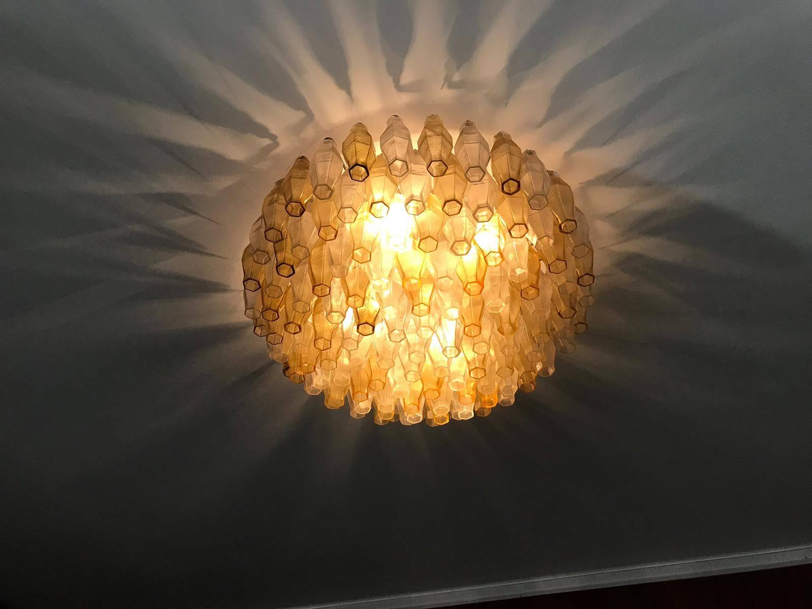 An amber-colored glass chandelier composed of several multi-shaped glasses hung on a white-painted metal fame with shiny nickel hardware by Venini. Italiano, circa 1970 Venini was founded in 1921 in the Italian glass capital of Murano, actually an
