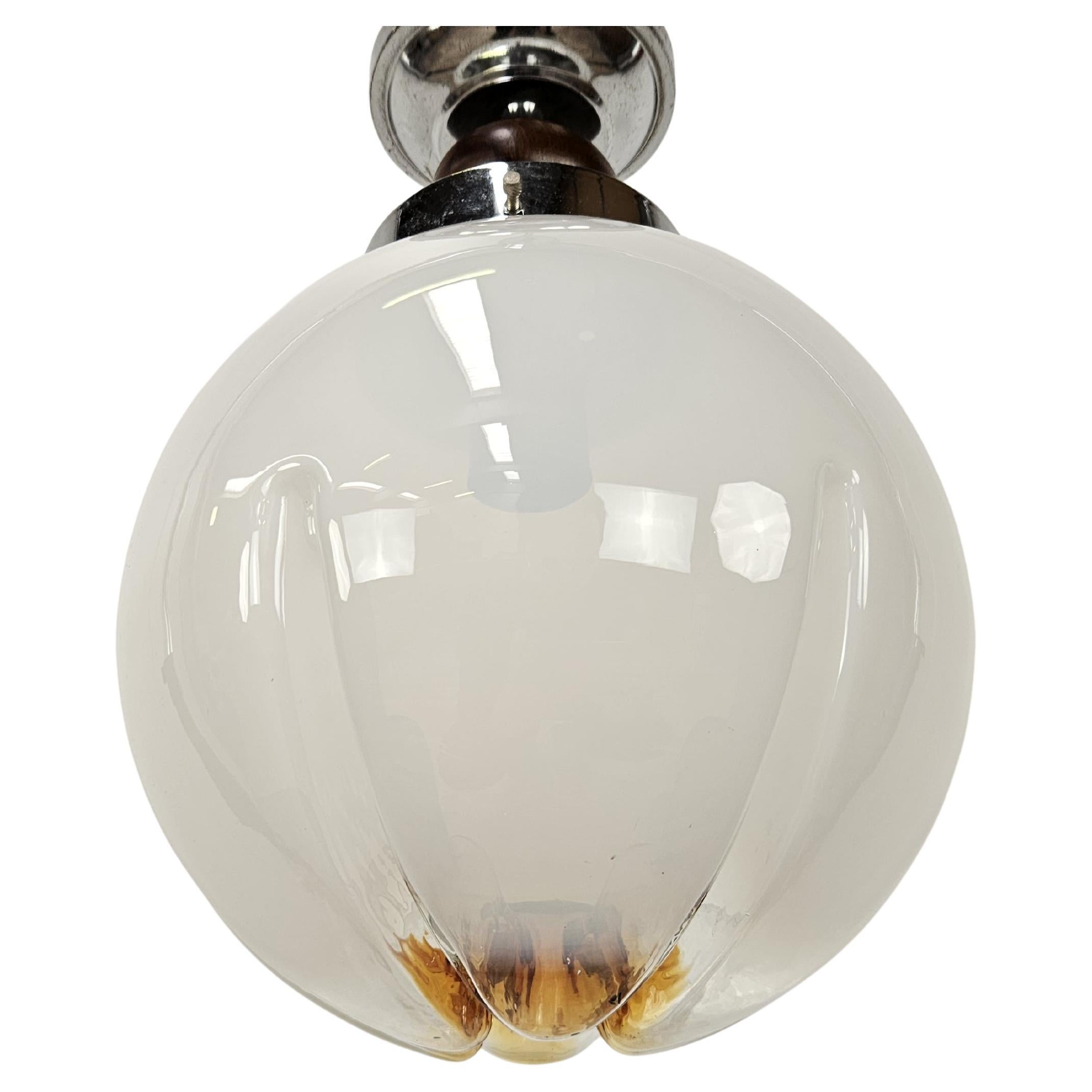Lampadario anni '60 con struttura in metallo decorato da un anello in legno e plafoniera in vetro di Murano.

Lampada vintage attribuibile dal design a Mazzega.

Normali segni d'usura, vetro perfetto.
