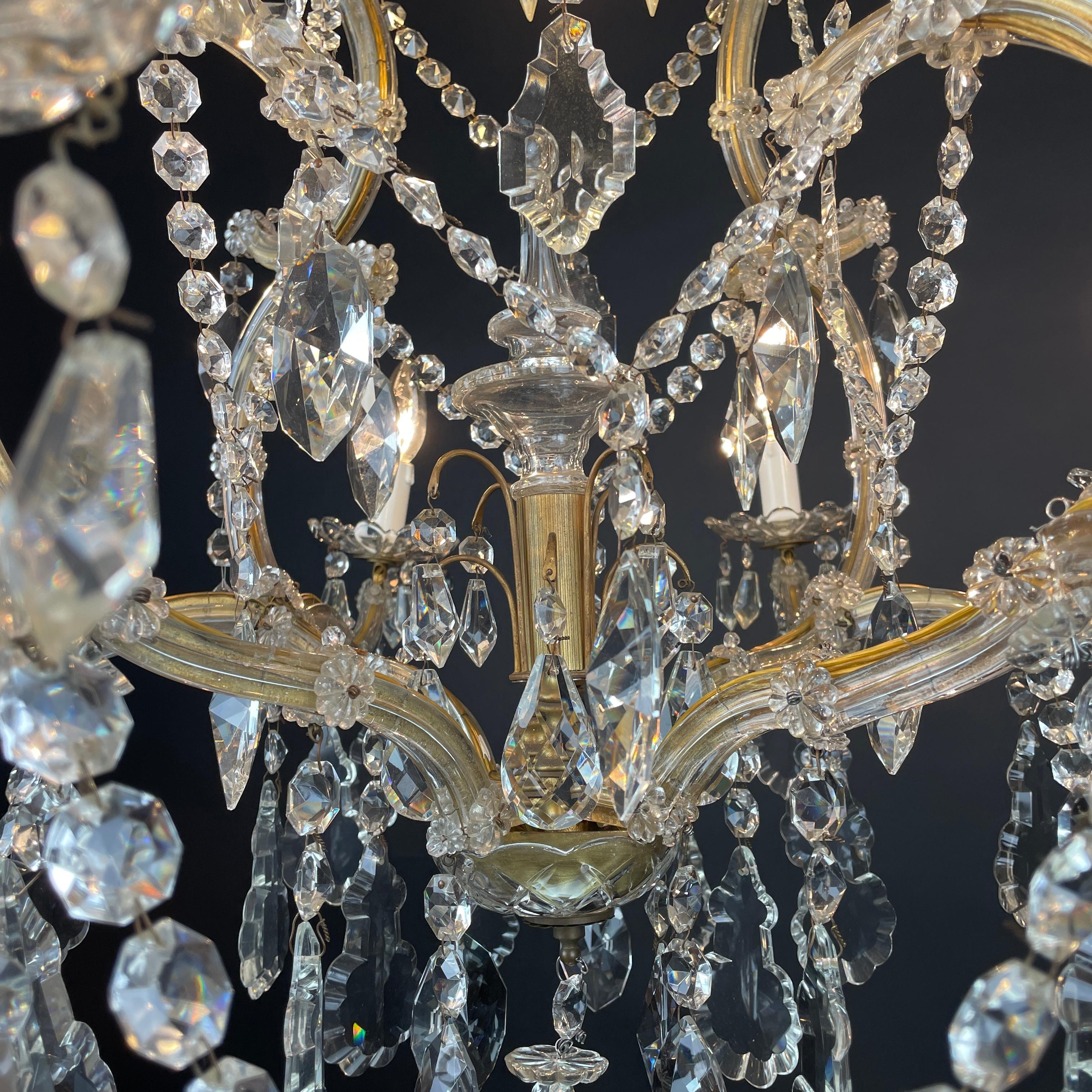Italian Chandelier In crystal with nine lights, eight curved arms with double volute ending with  flower-shaped bobèches and E14 bulbs plus an E27 light at the top in the center of the chandelier. It dates back to the 1950s and is in perfect