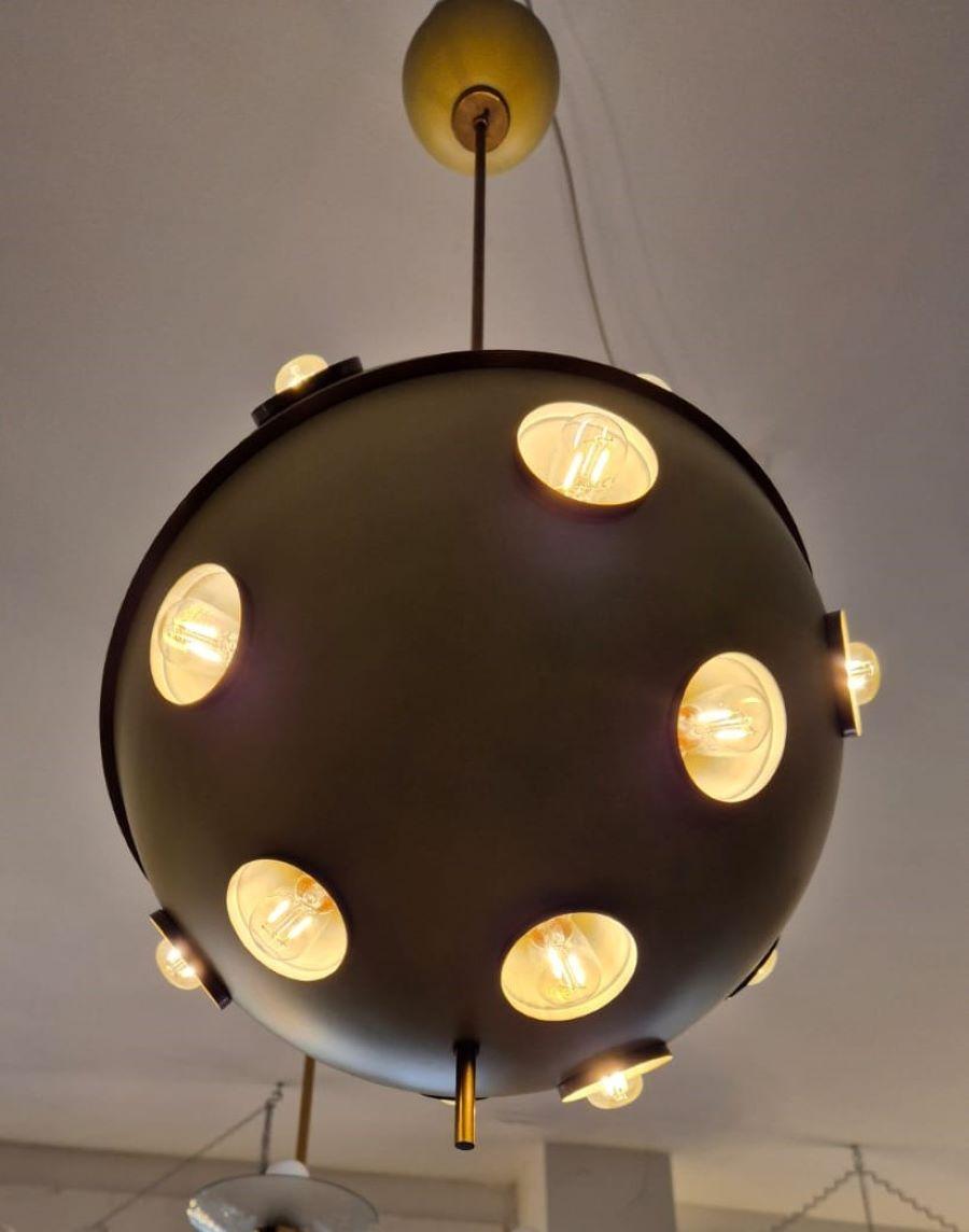 Lampada a sospensione modello 551 di Oscar Torlasco per Lumi anni' 60 circa.
Grande sfera in metallo giallo smaltato con anello diagonale in ottone. Il lampadario ha 18 lampadine con alloggio incavato nella sfera e circondato da un piccolo anello in