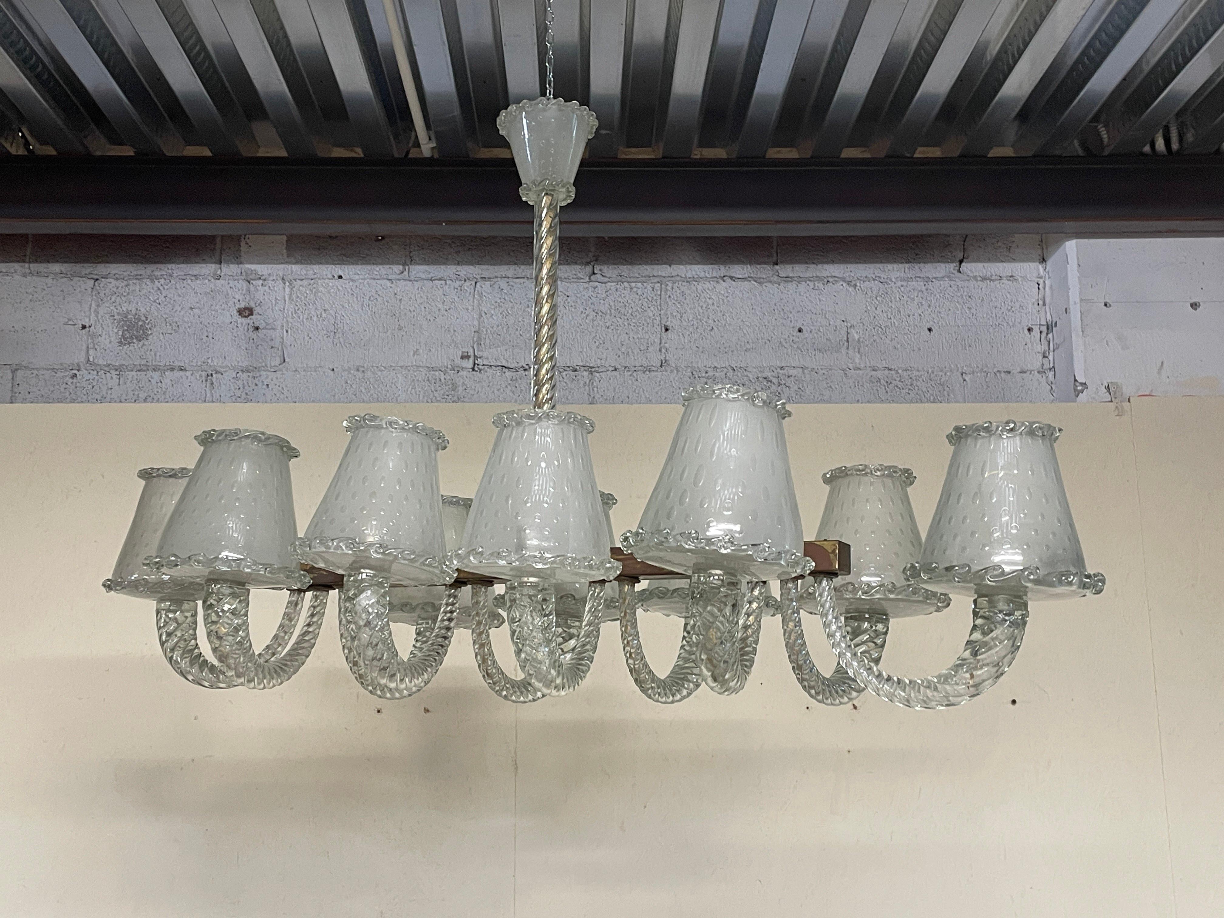 Affascinante lampadario monumentale di produzione Seguso risalente agli anni '30.

Dalla base in ottone si snodano 10 vetri a torchon che collegano i paralumi in vetro acidato di Murano.

Un capolavoro dell'arte vetraia di Seguso che non passa di