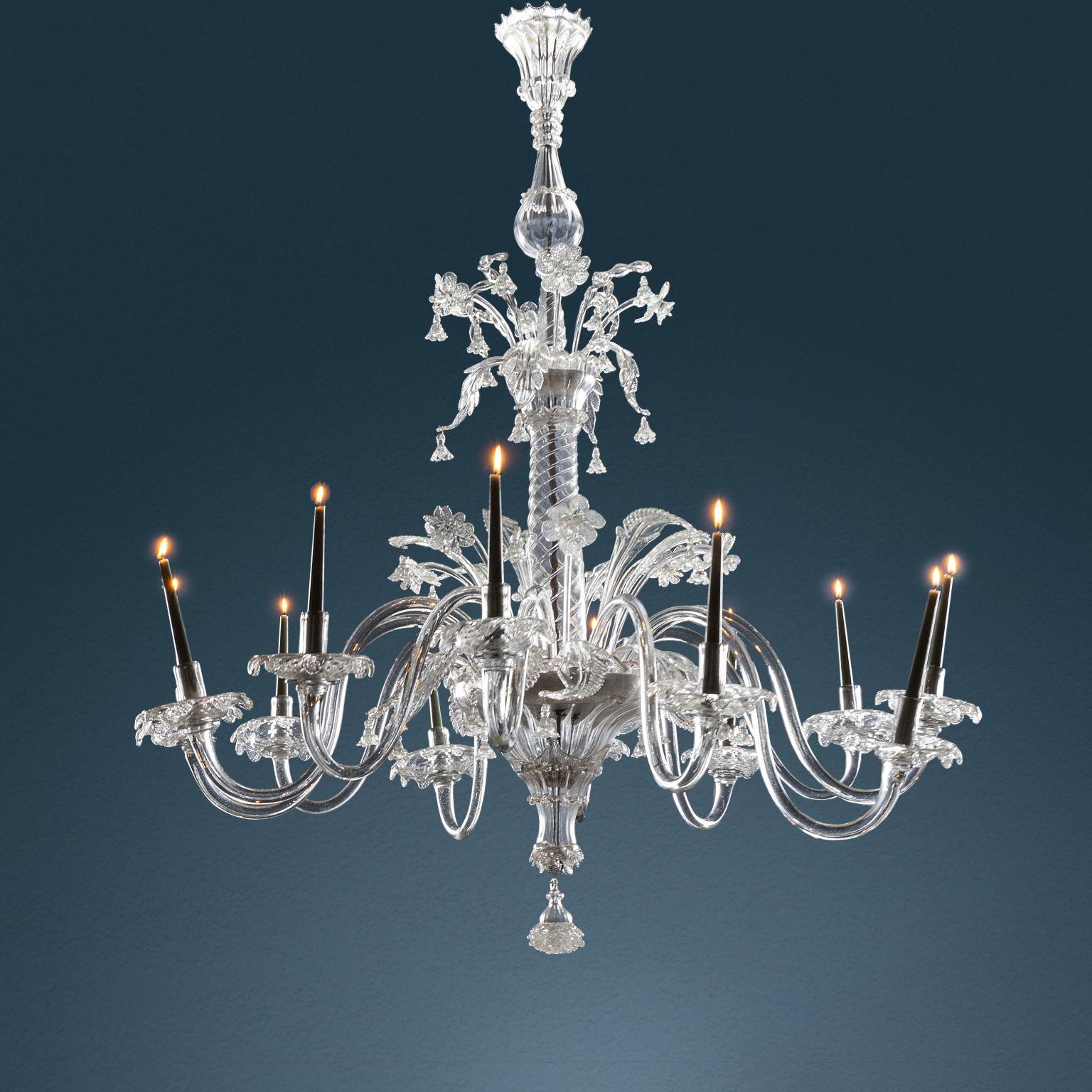 Grande lampadario Murano in vetro soffiato trasparente a dodici fiamme, prodotto dell'arte veneziana di fine XVIII secolo. L'intero apparato è sorretto centralmente da un fusto a colonna liscia riproducente motivo tortile, dotato di anima metallica.