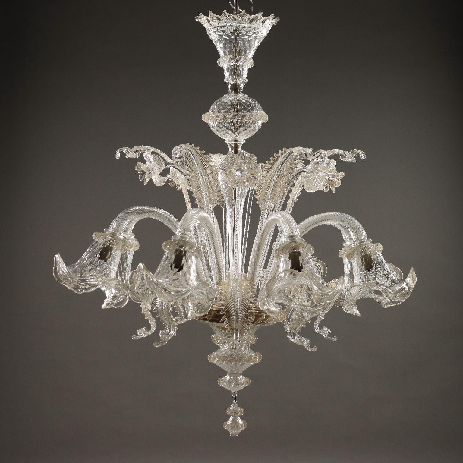 Lampadario Veneziano in vetro soffiato trasparente e inserti dorati, otto luci alternate ad altrettante foglie pendenti, parte superiore composta da foglie mosse e fiori.
Murano, XX Secolo.